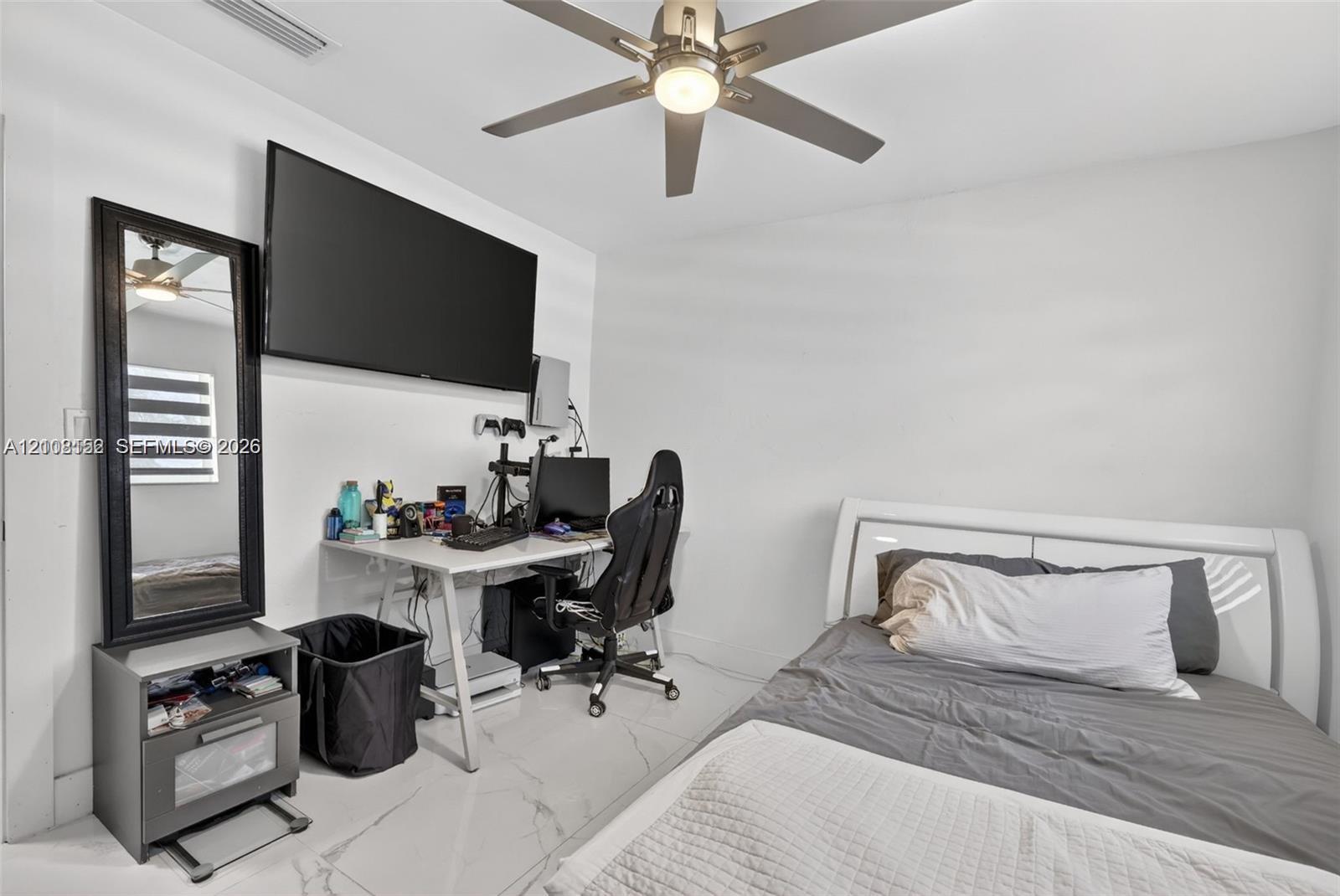 Interior space featuring white stone-finish flooring, a wall-mounted ceiling fan with integrated lighting, and neutral wall tones