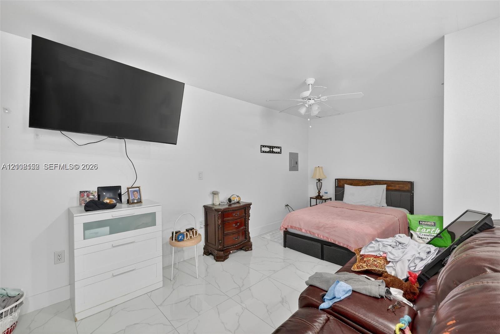 Large-format tile flooring, neutral walls, and a ceiling-mounted light fixture with fan