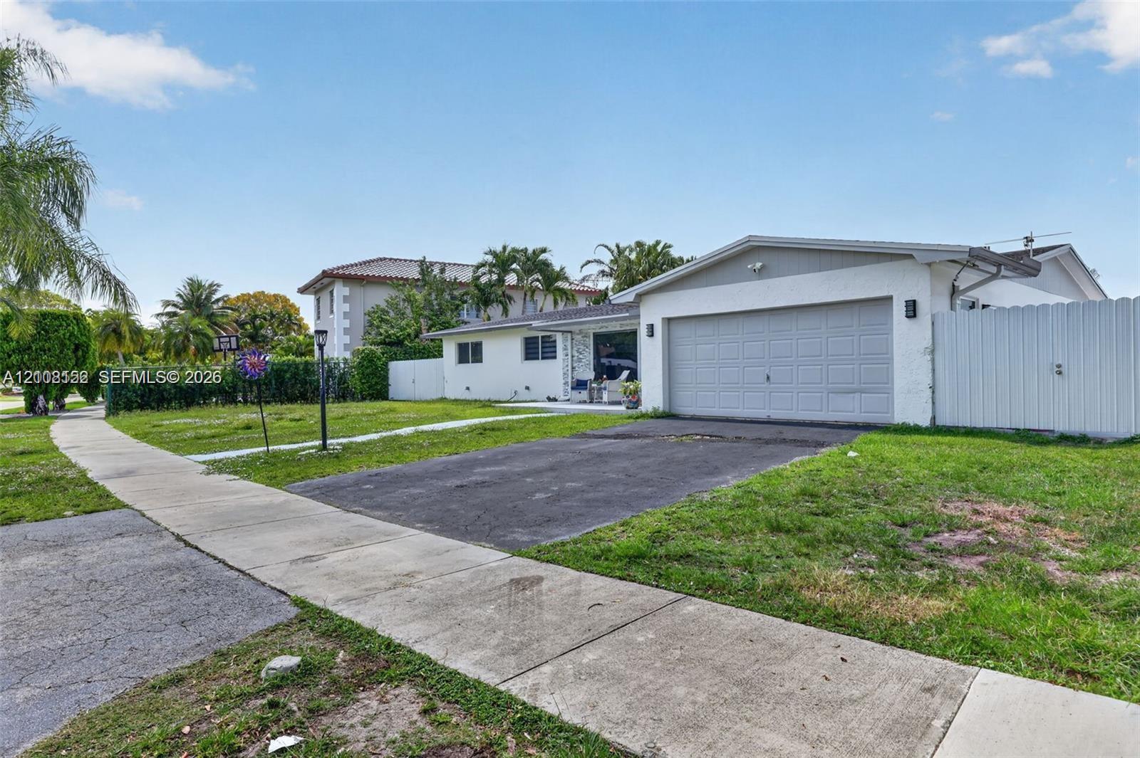 Single-story exterior featuring a painted stucco facade, an attached one-car garage, and a tall vinyl privacy fence