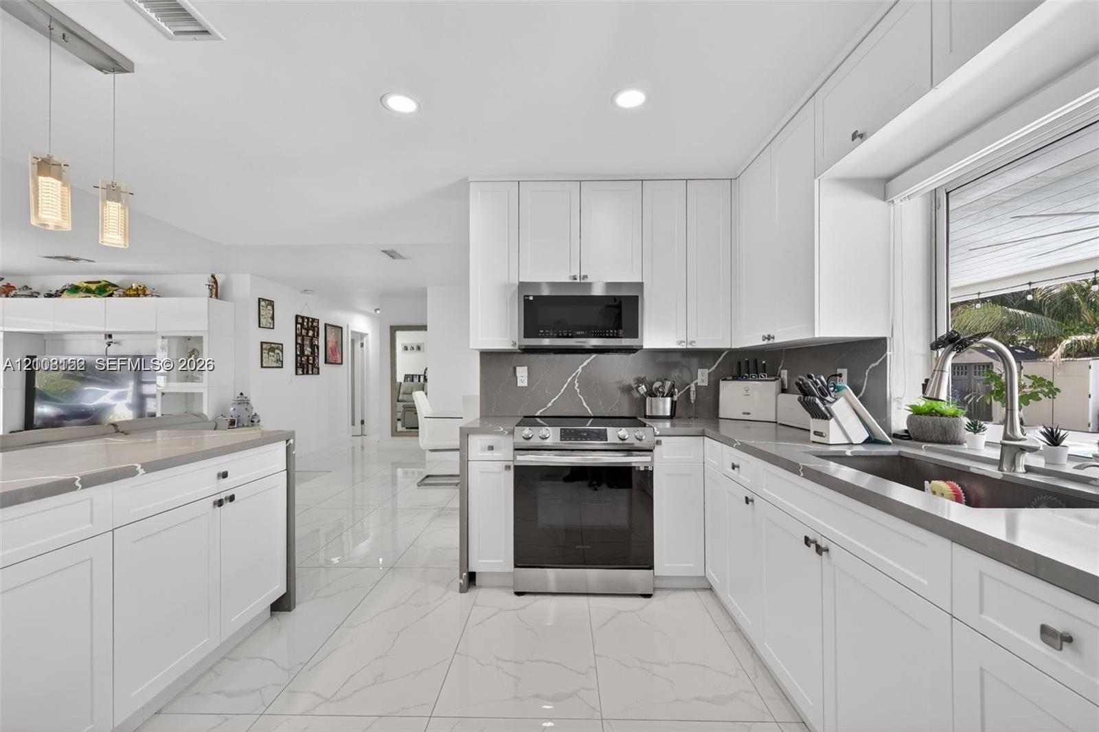 Kitchen featuring white shaker-style cabinetry, solid-surface countertops, tile flooring, recessed lighting, and stainless steel appliances