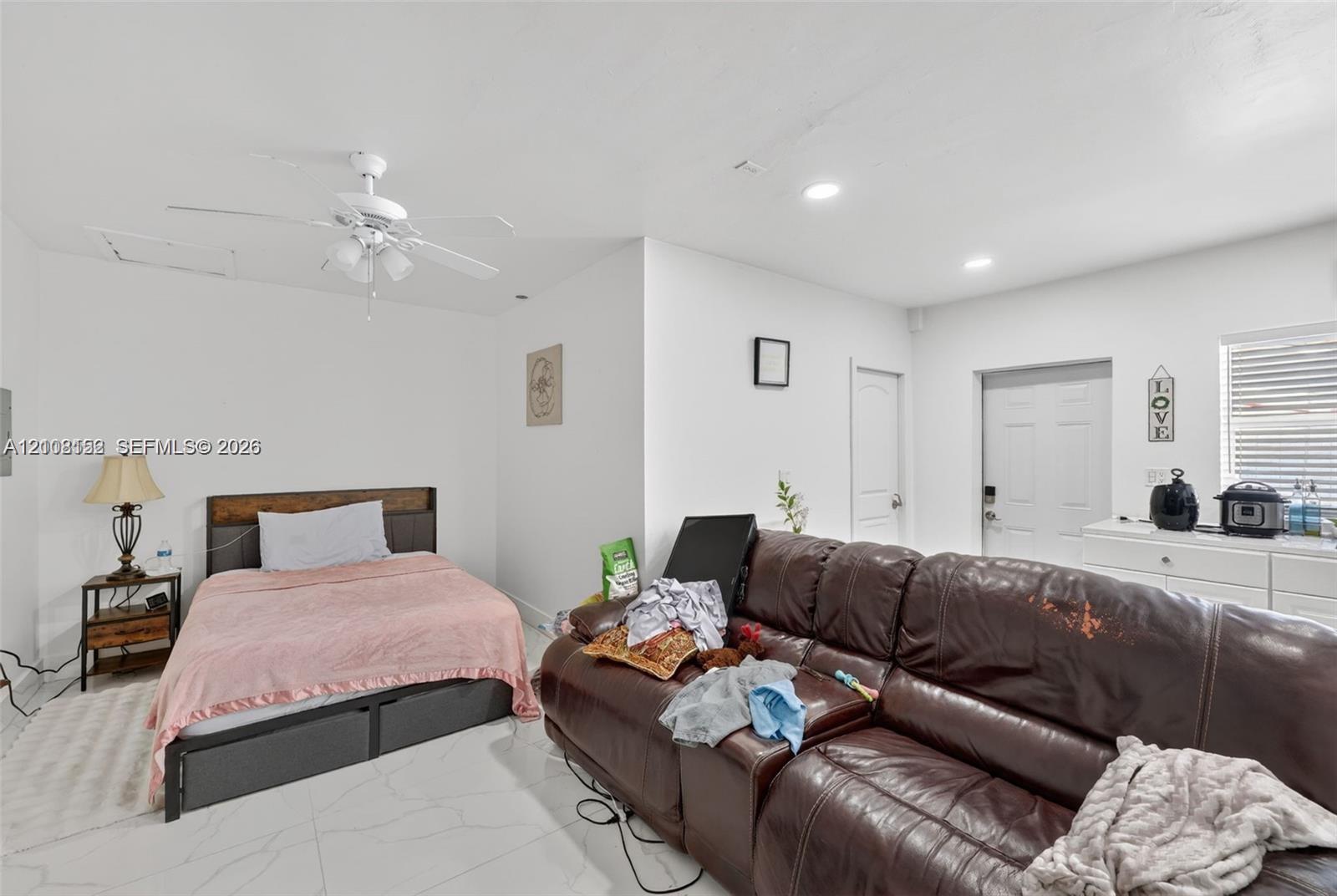 Spacious interior featuring white tile flooring, recessed lighting, and a white ceiling fan with integrated lighting