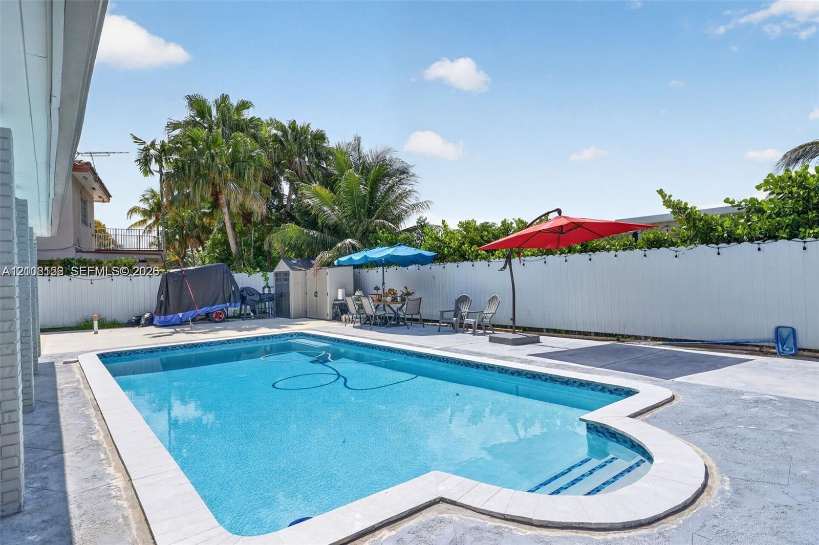 In-ground swimming pool with built-in stairs, concrete patio surround, and white vinyl privacy fencing