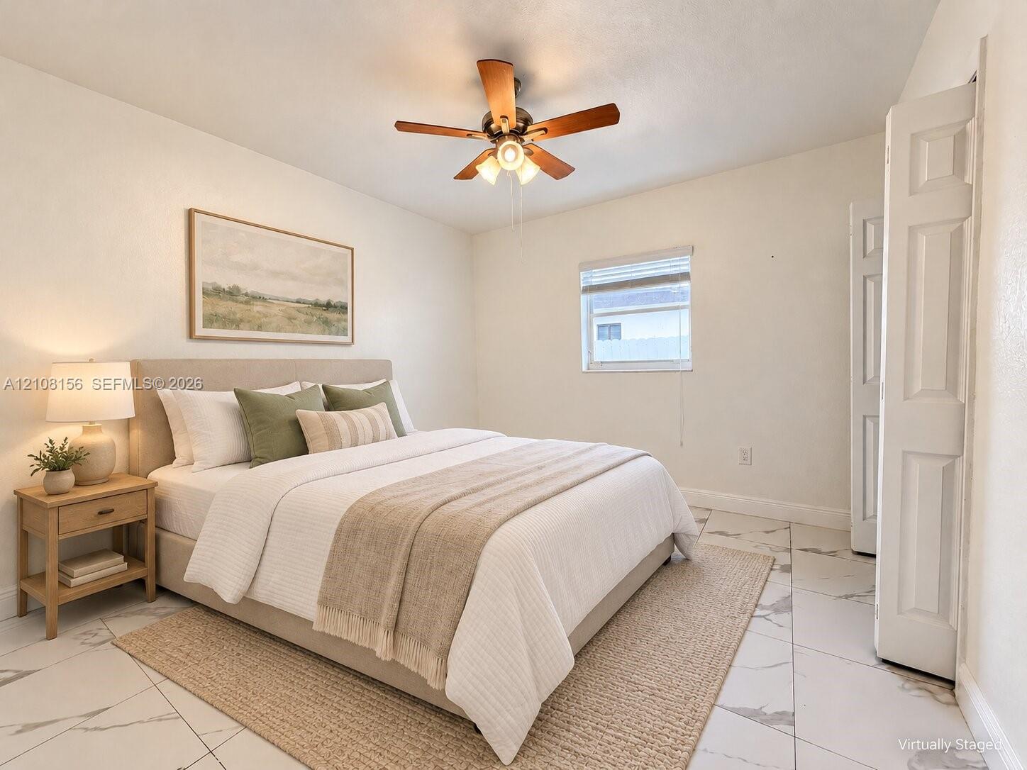 Neutral-toned interior featuring large-format tile flooring, a multi-blade ceiling fan with integrated lighting, and a bifold closet door