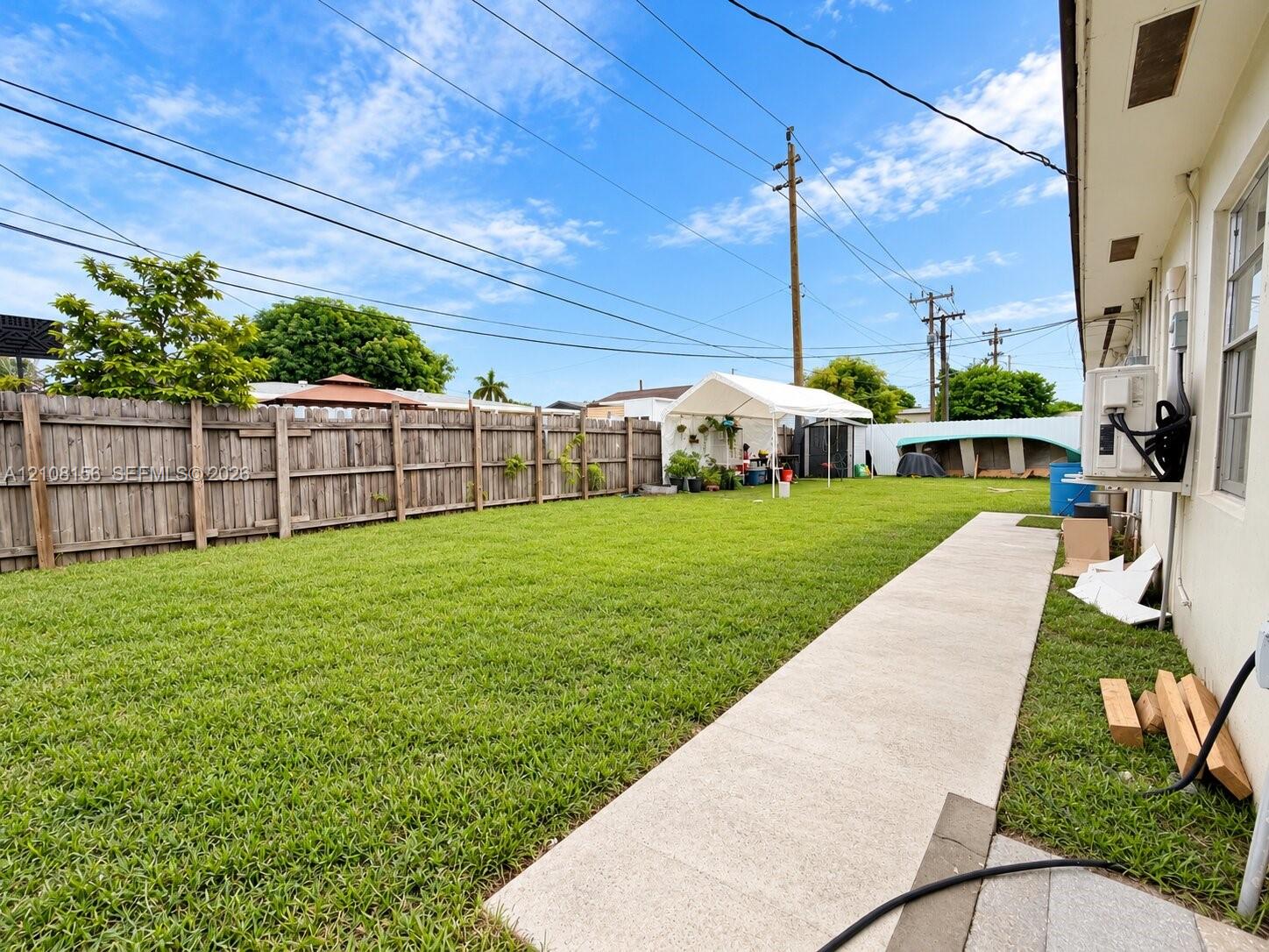 Expansive backyard featuring a level grass lawn, perimeter wood privacy fencing, and a concrete pathway