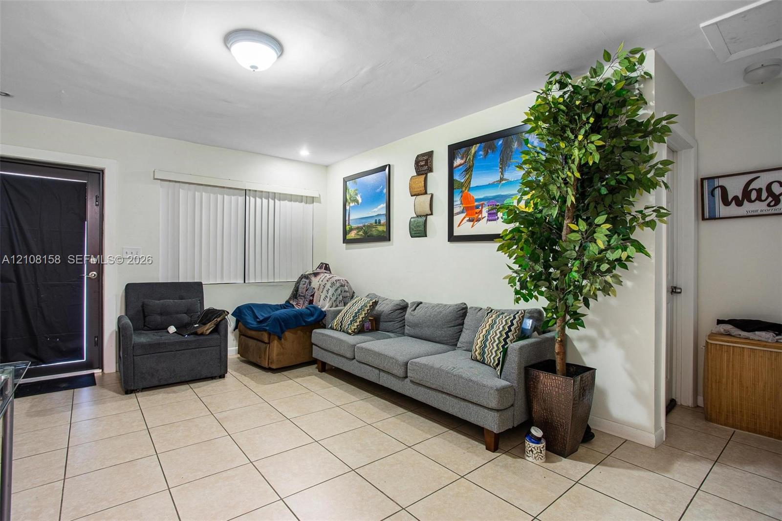 Neutral-toned ceramic tile flooring, flush-mount ceiling lighting, and a glass-paneled exterior entry door with vertical blinds