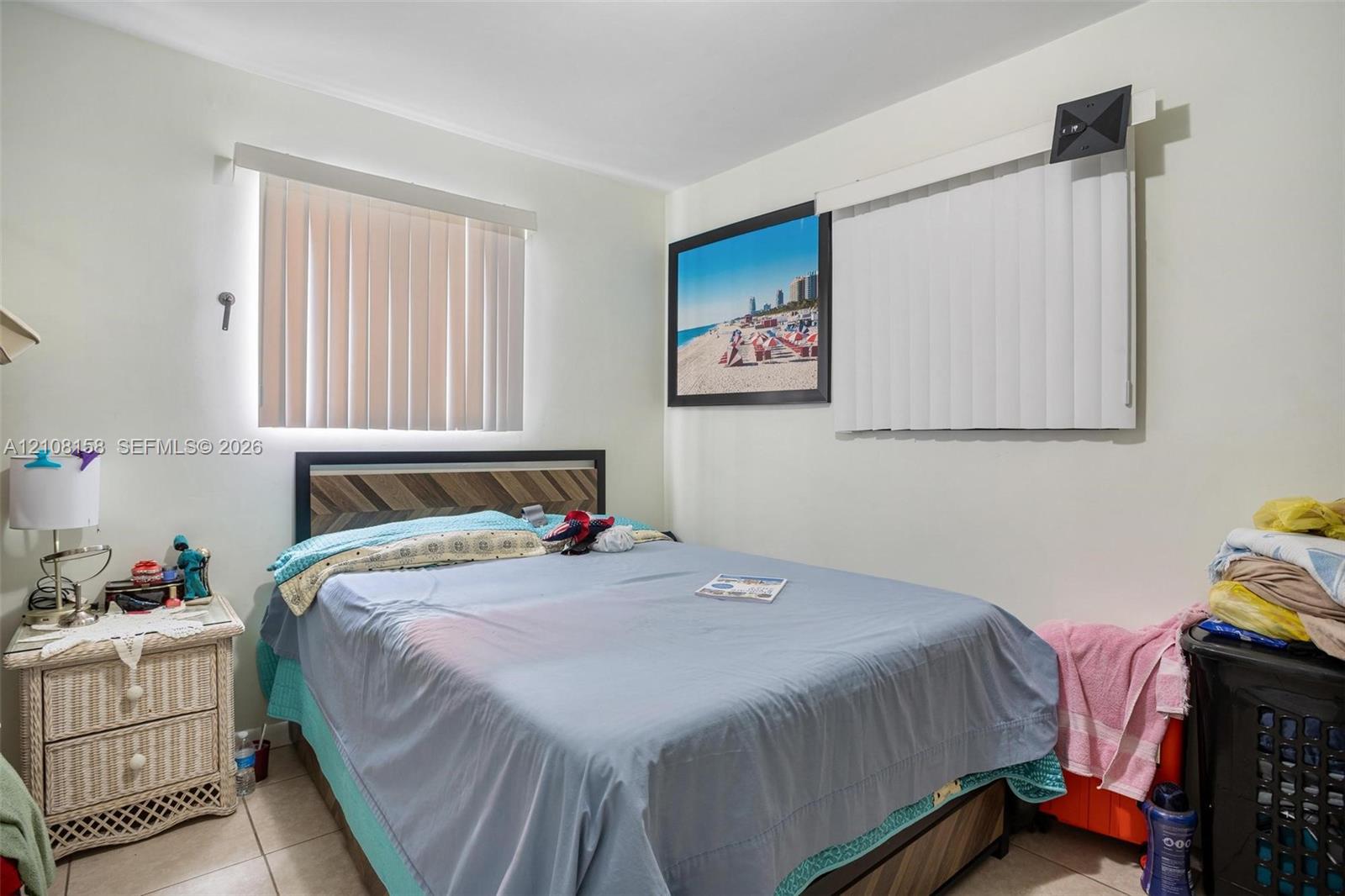 Neutral wall tones featuring dual windows with vertical blinds and large-format tile flooring