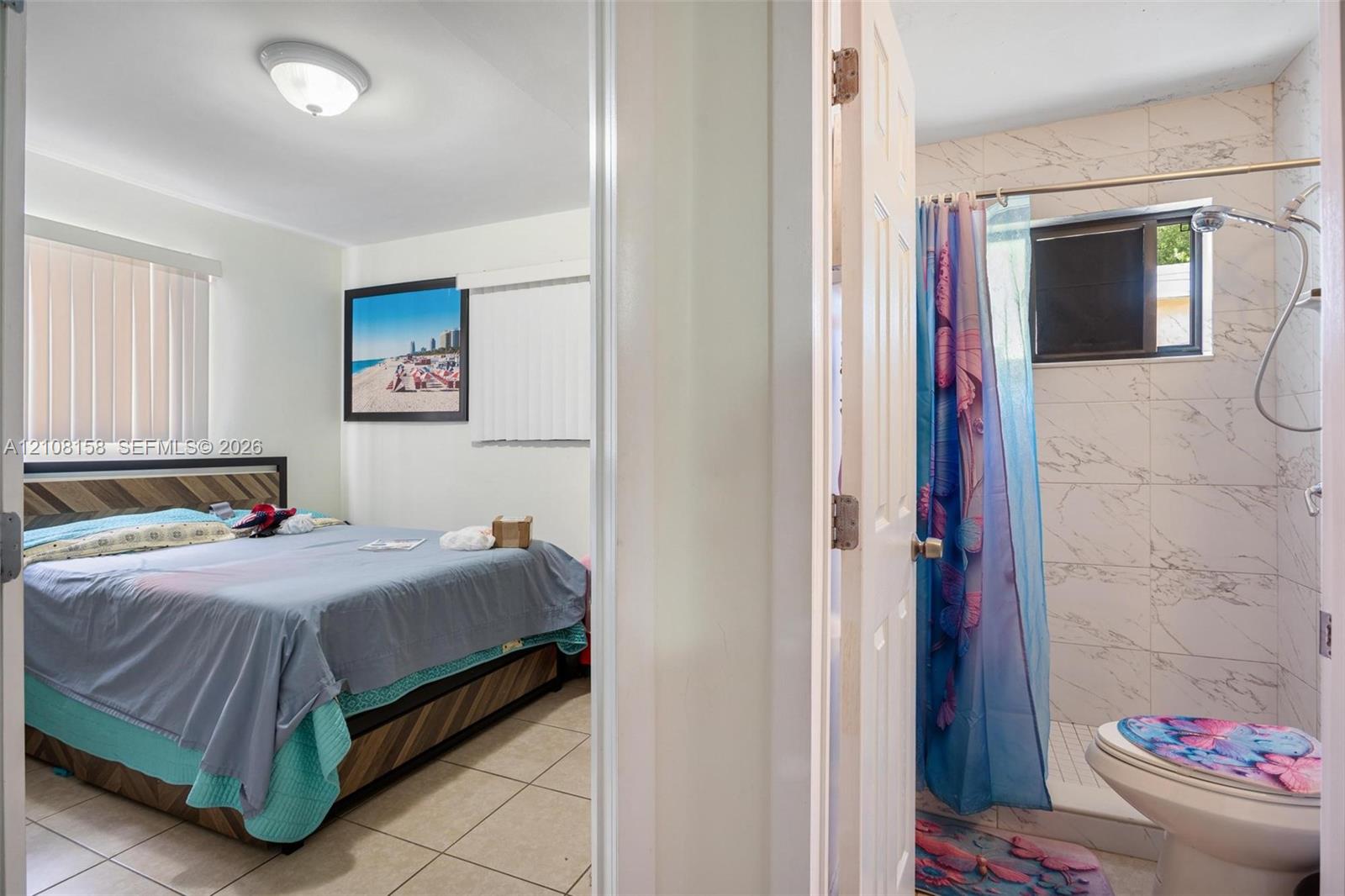 Ceramic tile flooring, shower stall with light-colored tile surround, and window blinds