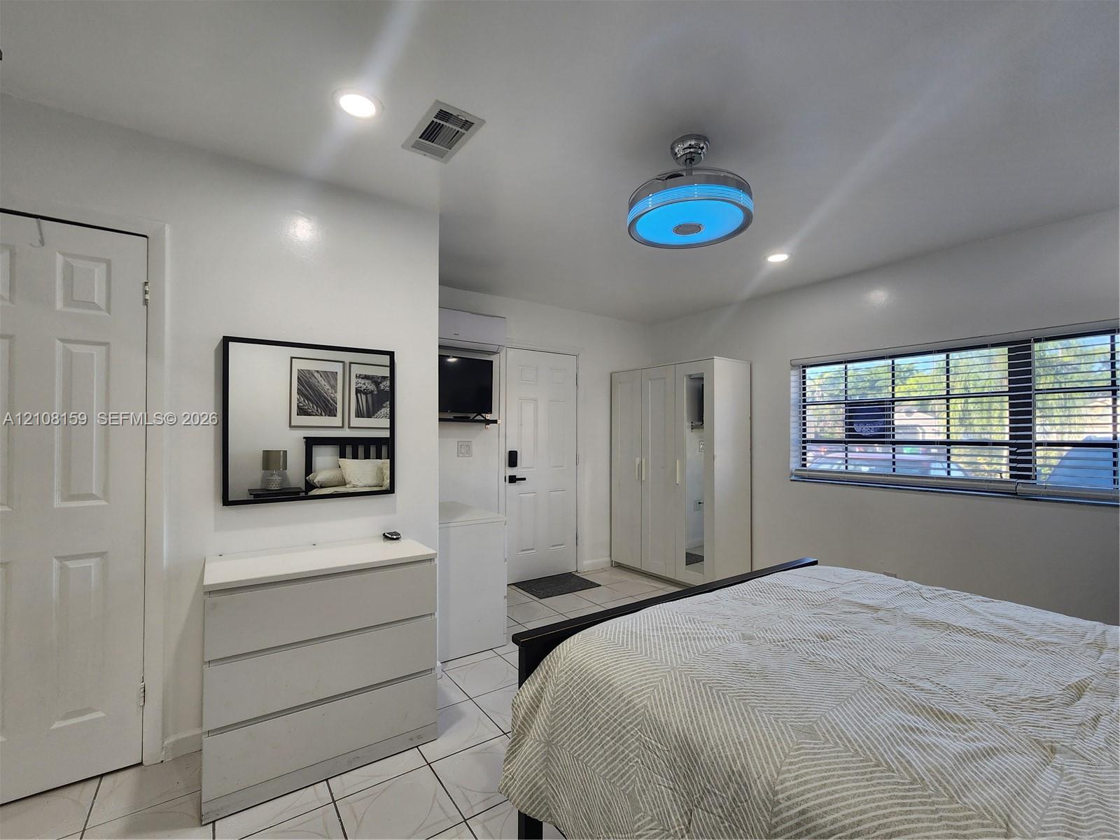 Interior space featuring neutral wall tones, large-format tile flooring, recessed ceiling lighting, a contemporary drum-style ceiling fixture, and expansive windows fitted with horizontal blinds