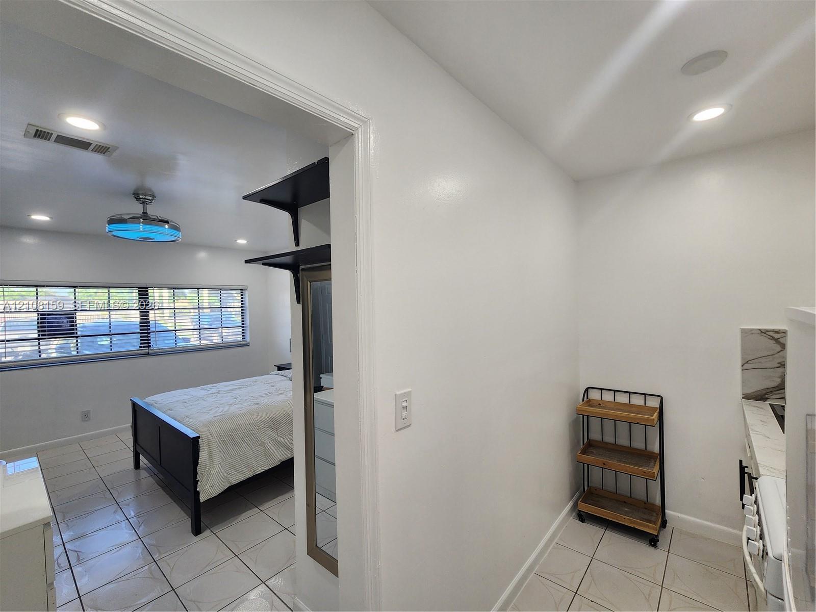 Interior space featuring neutral wall tones, large-format tile flooring, recessed ceiling lighting, and built-in shelving