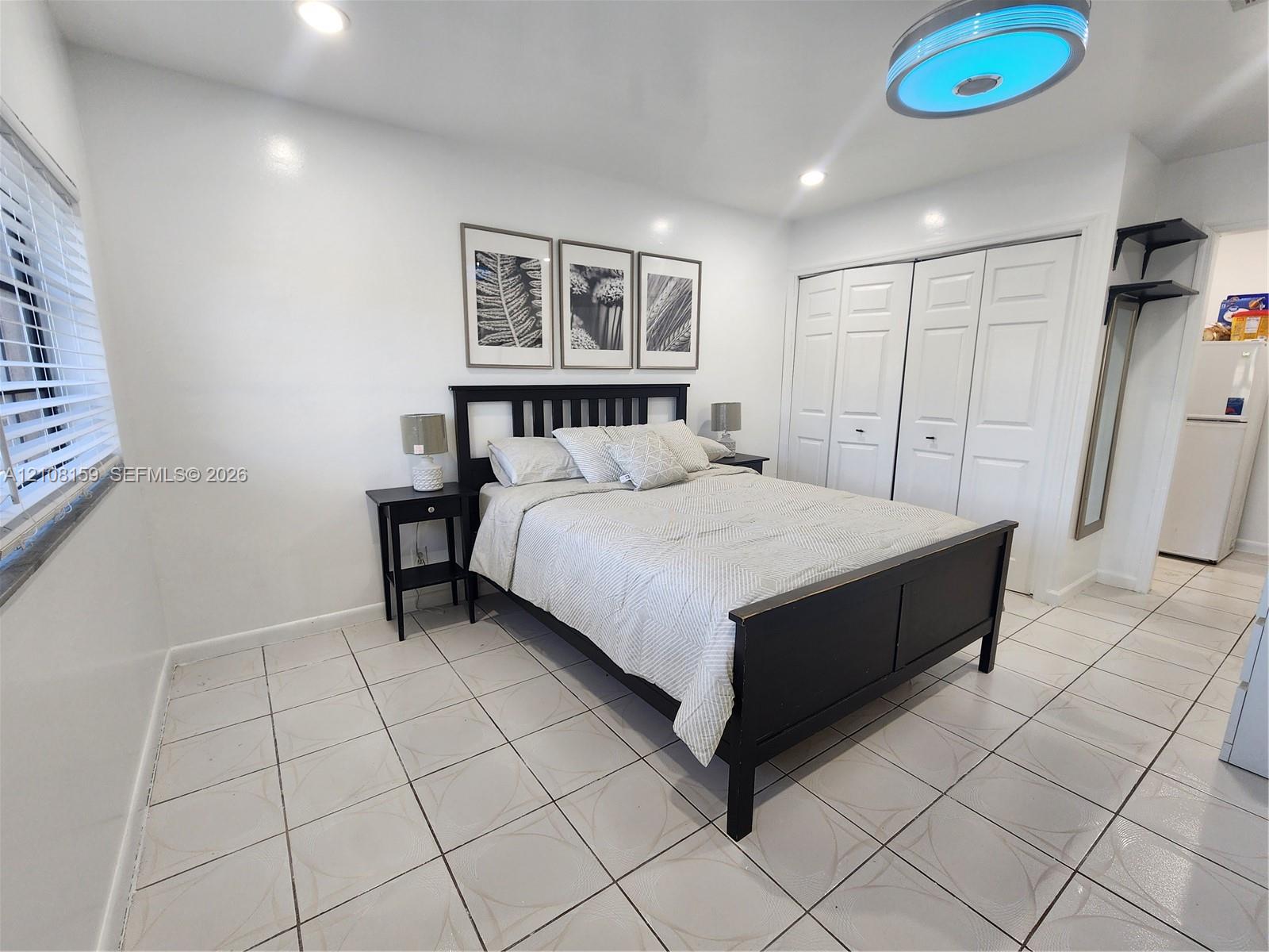 Neutral-toned tile flooring, recessed lighting, double-door closet with paneled detail, and window with adjustable blinds