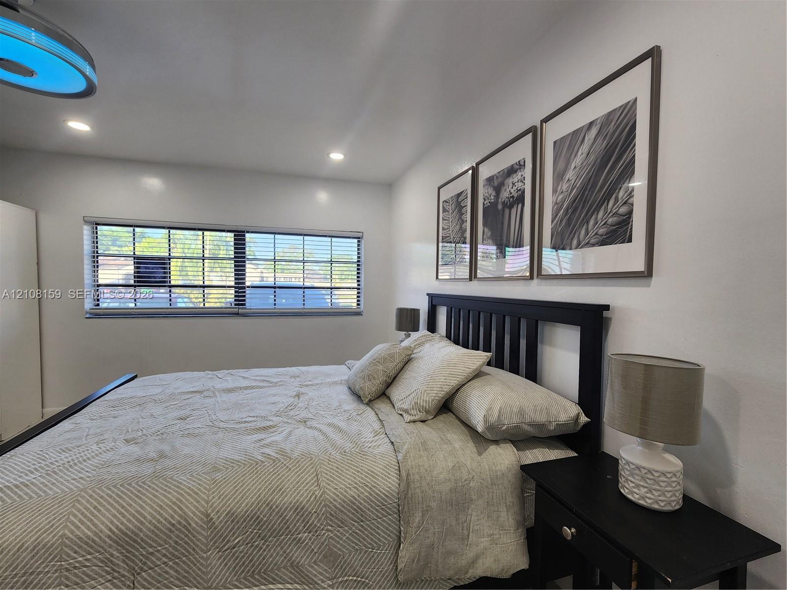 Recessed ceiling lighting, wide horizontal window with integrated blinds, and smooth-finish walls