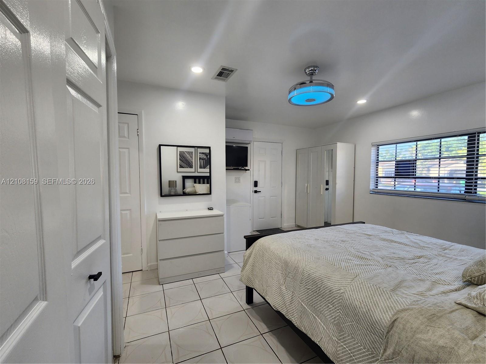Interior room featuring large-format tile flooring, recessed lighting, a modern multi-functional ceiling fixture, and horizontal window blinds
