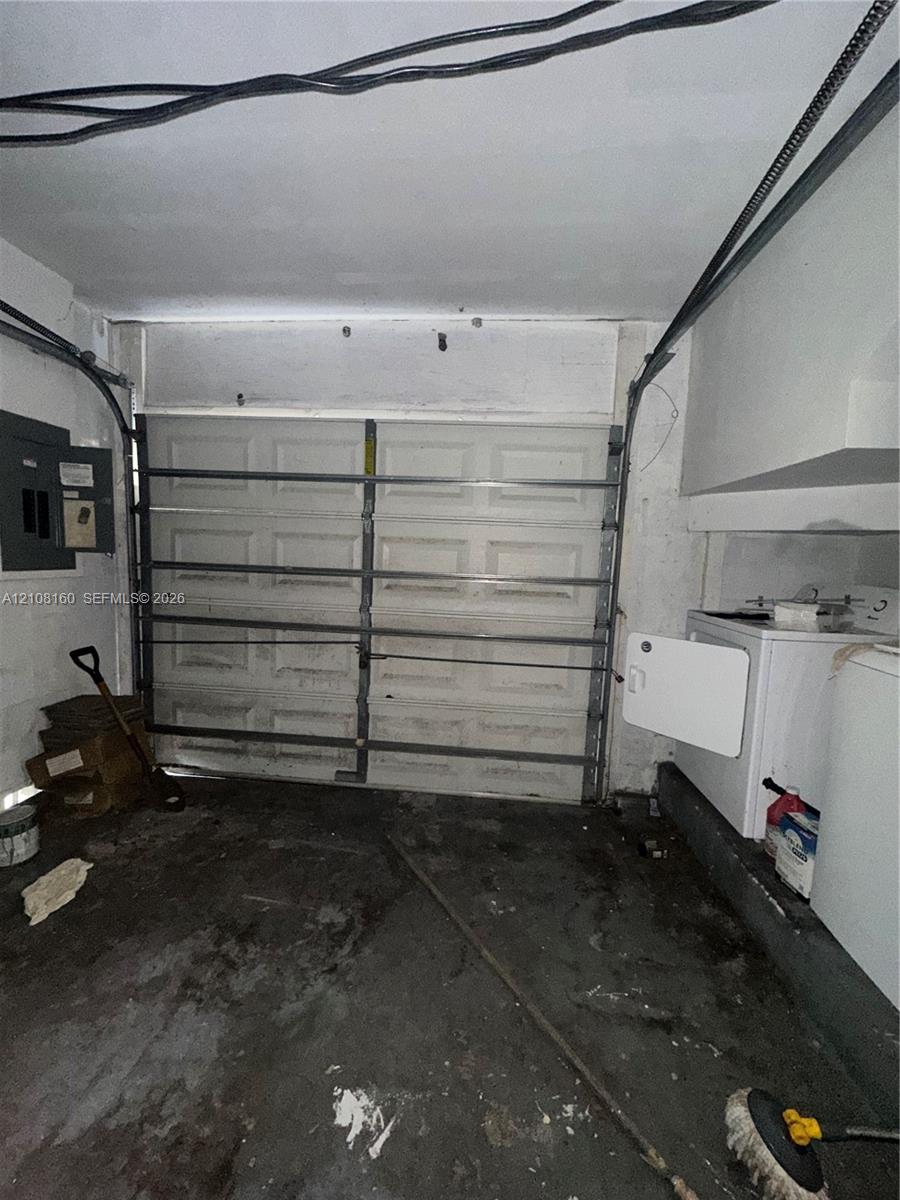 Enclosed garage space featuring a paneled sectional garage door, concrete flooring, and an integrated electrical service panel