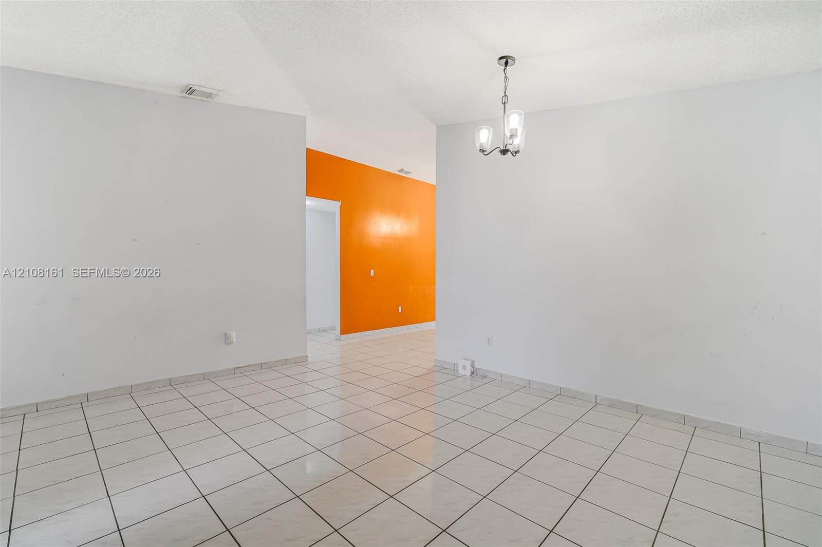 Large-format ceramic tile flooring paired with a multi-arm, glass-shade pendant light fixture and vaulted ceilings