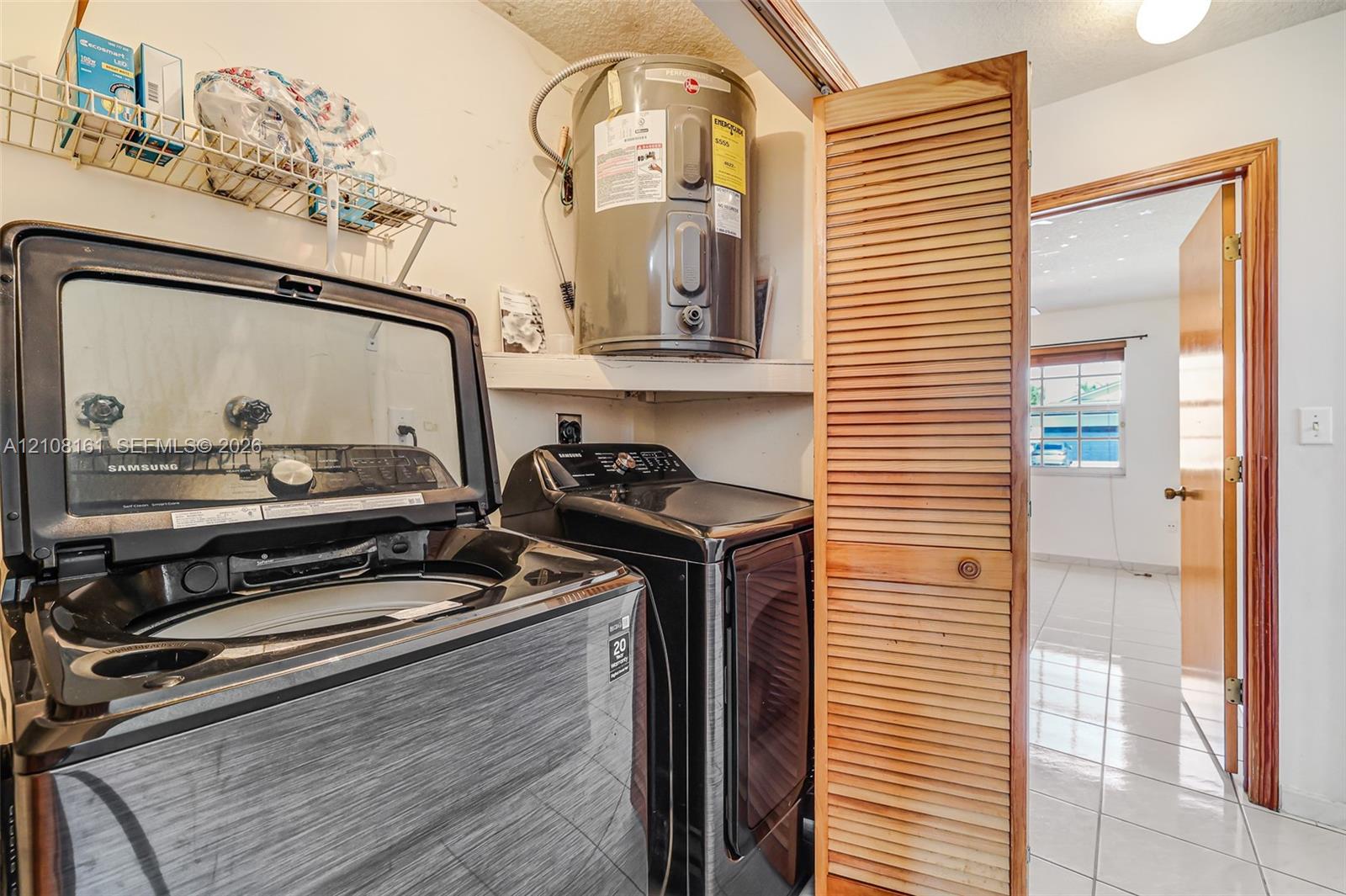 Laundry closet featuring louvered wood doors, integrated shelving, and a water heater