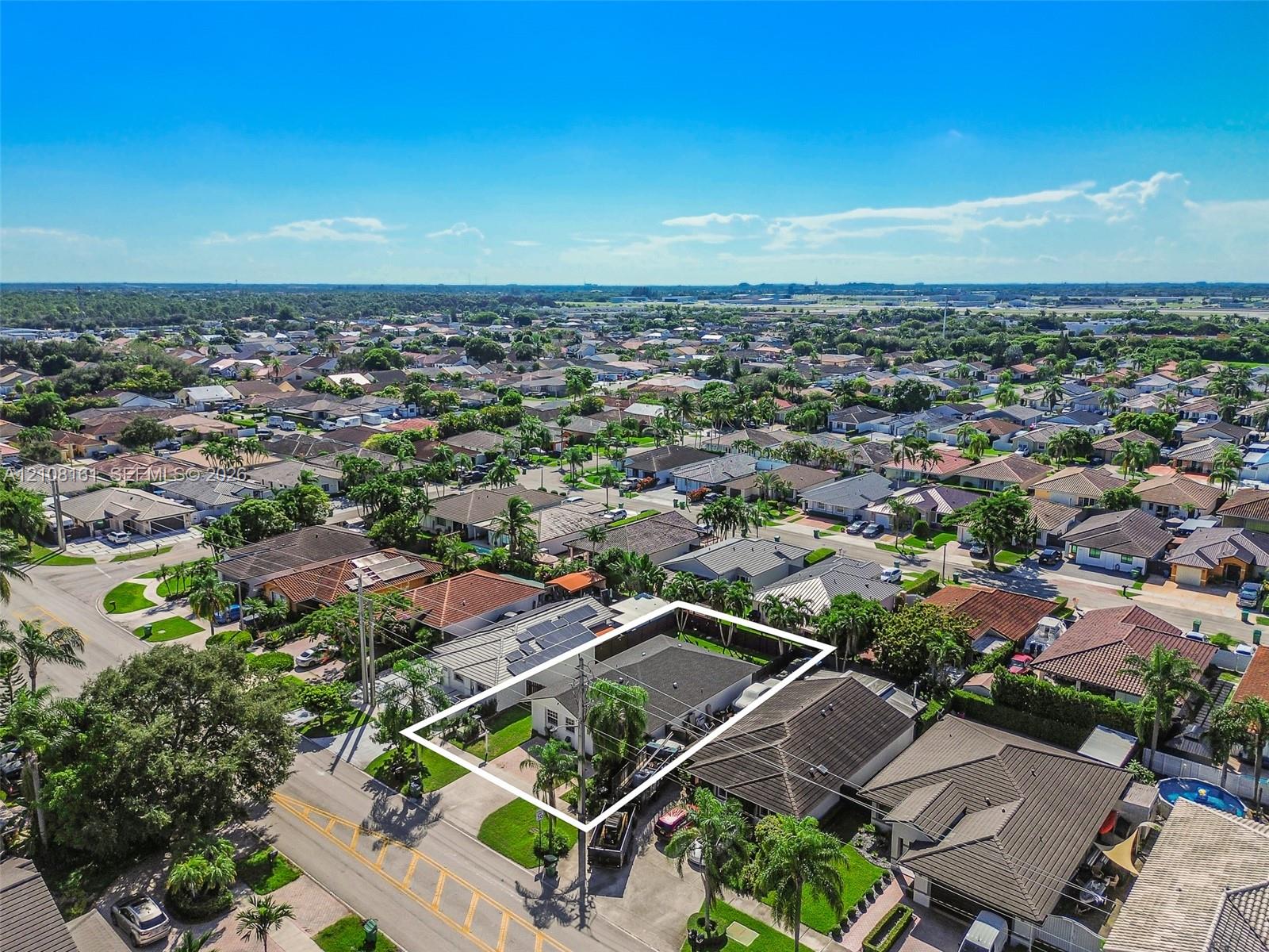 Aerial perspective of property featuring a fenced perimeter, solar panels, and manicured landscaping