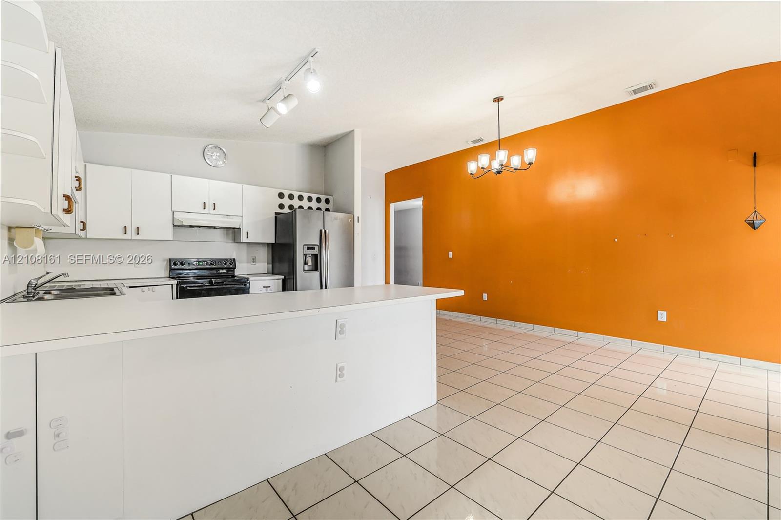 Kitchen featuring a peninsula countertop, white cabinetry, built-in stainless steel appliances, track lighting, and tiled flooring
