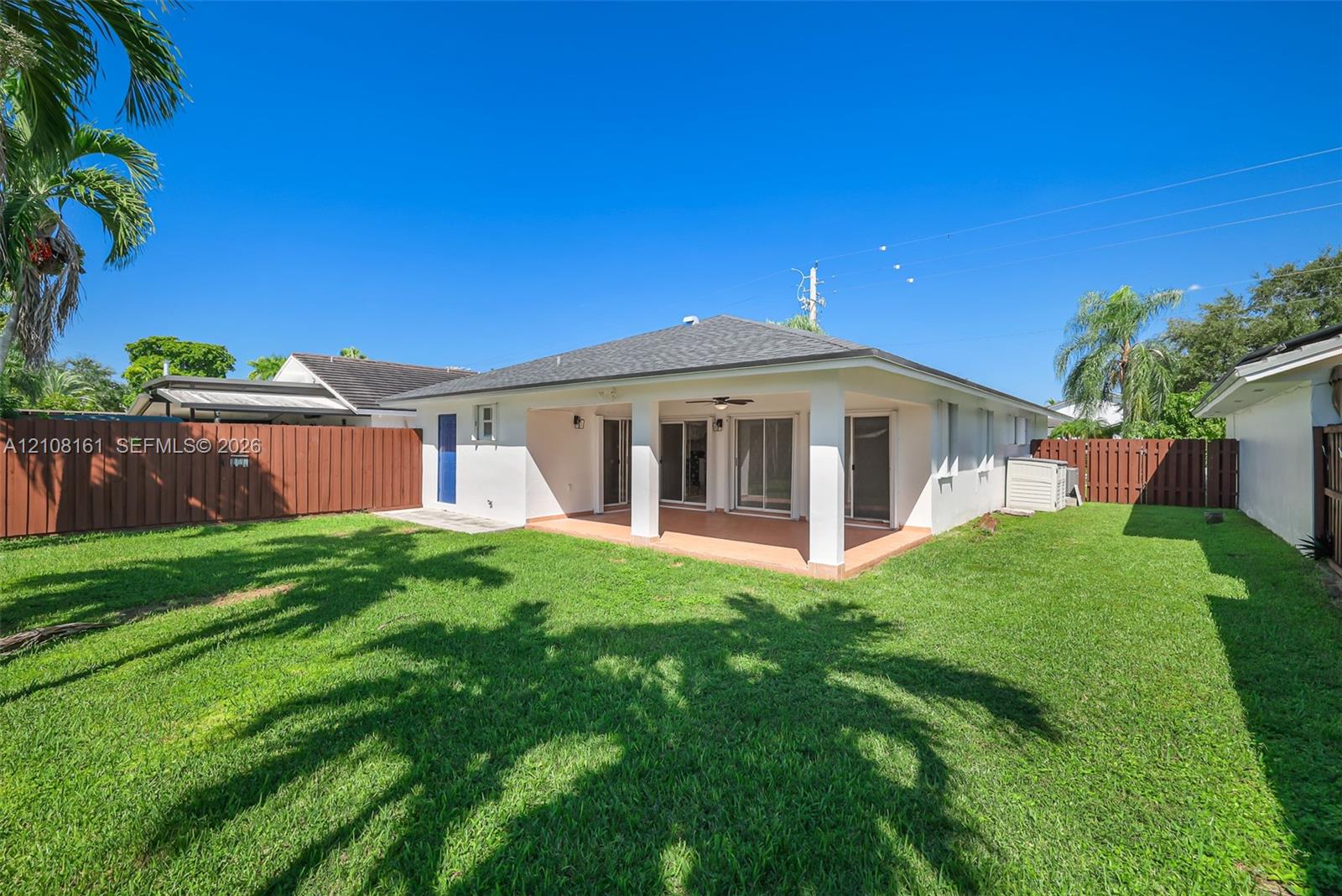 Rear exterior featuring a covered patio, tiled flooring, sliding glass doors, and a fenced backyard