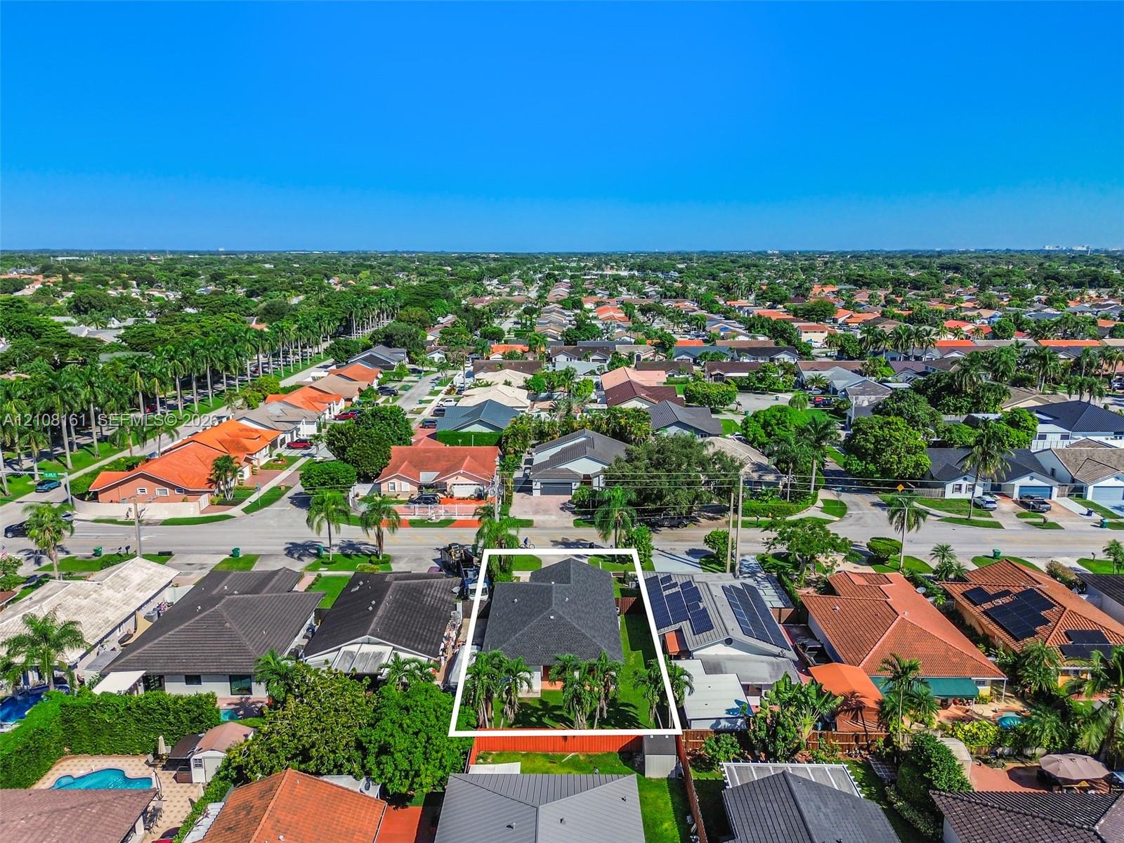 Aerial perspective of a single-family residence featuring a dark shingle roof, a landscaped backyard, and a fenced perimeter