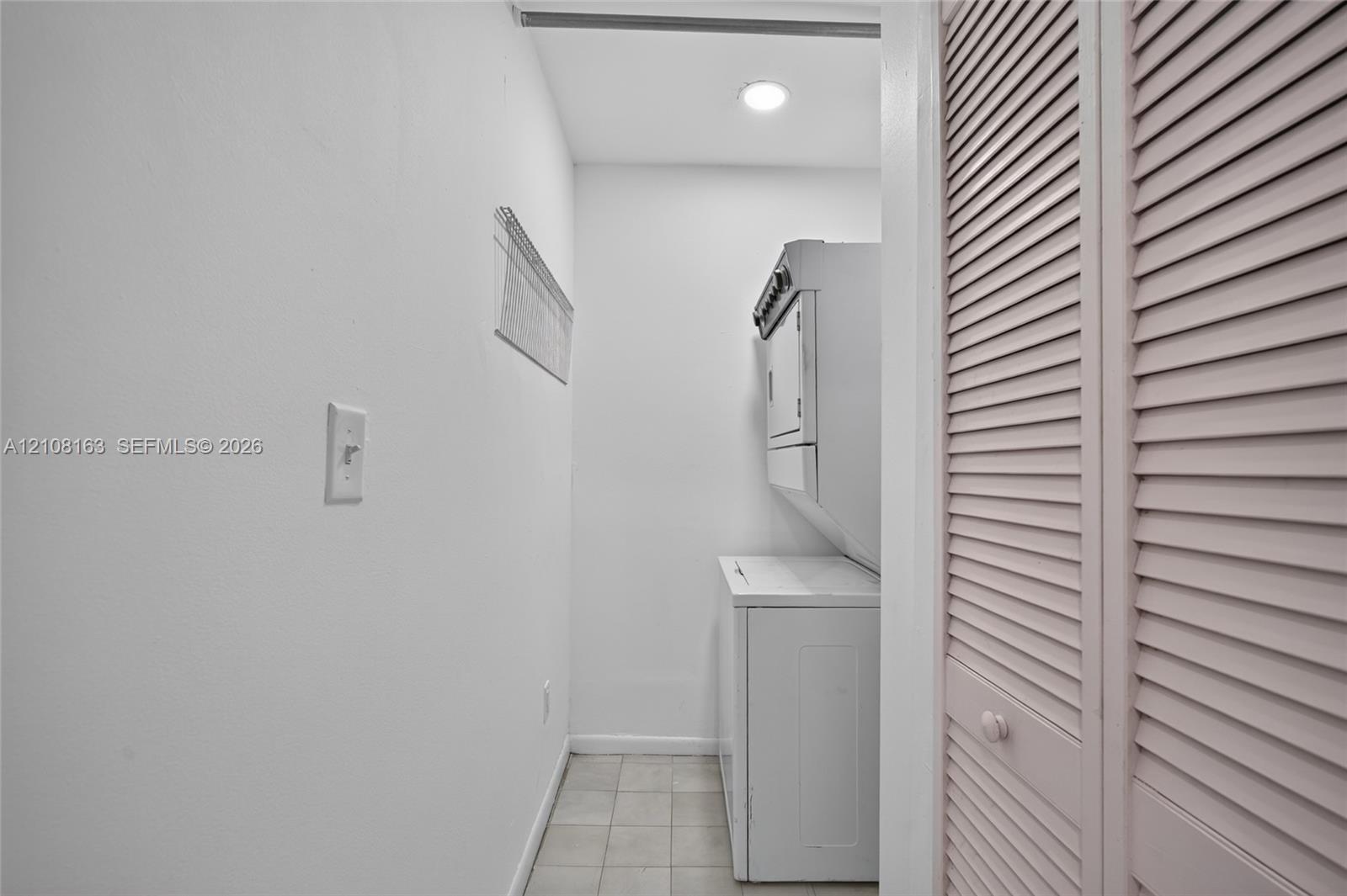 Bathroom featuring a stone-finish tile tub surround, white vanity cabinet with a stone-finish countertop, undermount sink, and wood-finish tile flooring