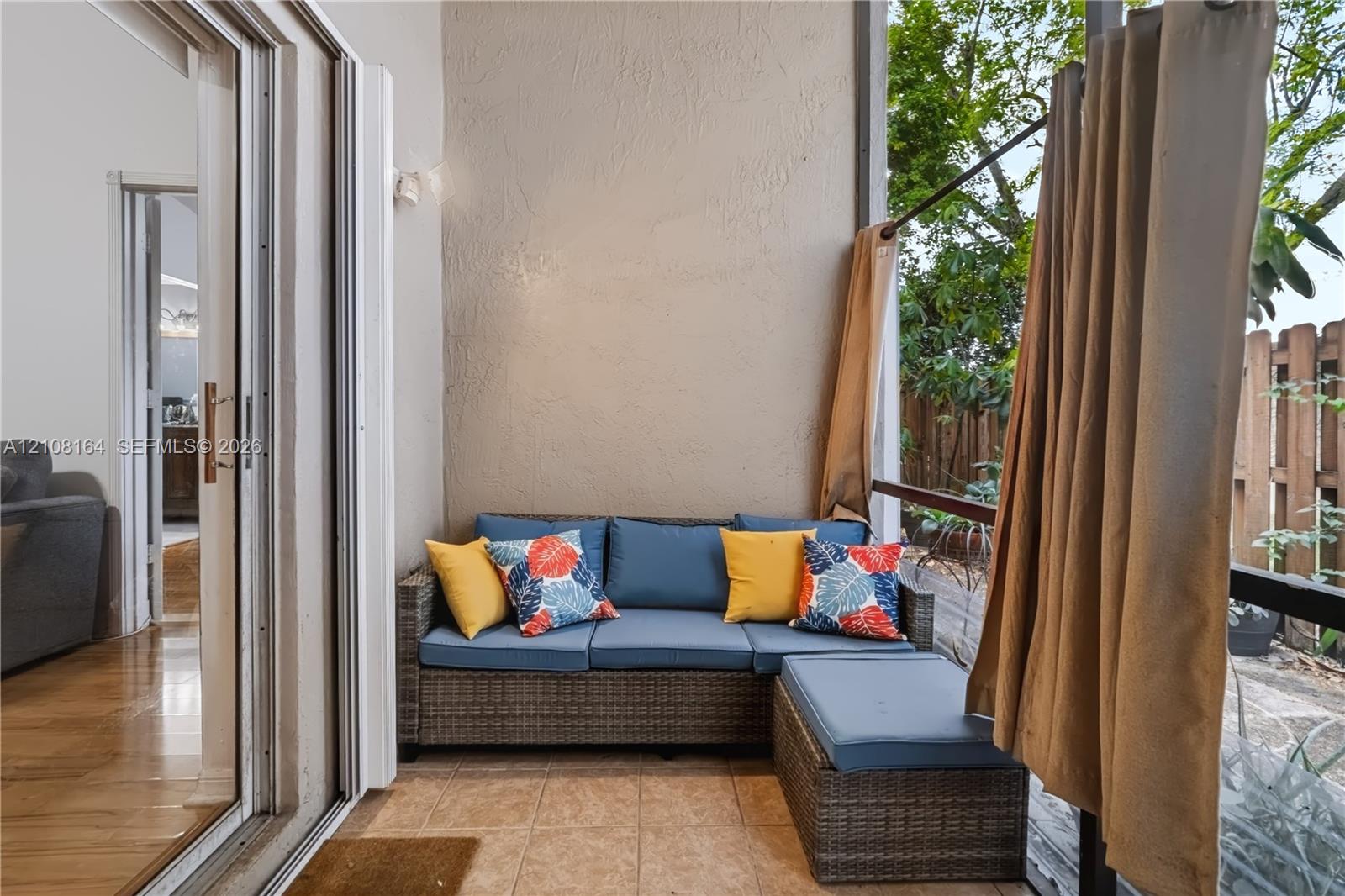 Covered patio featuring ceramic tile flooring, textured stucco wall, and metal-framed screen enclosure