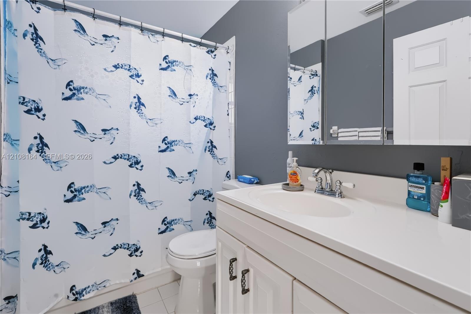 White vanity with an integrated countertop sink, chrome dual-handle faucet, and mirrored medicine cabinet