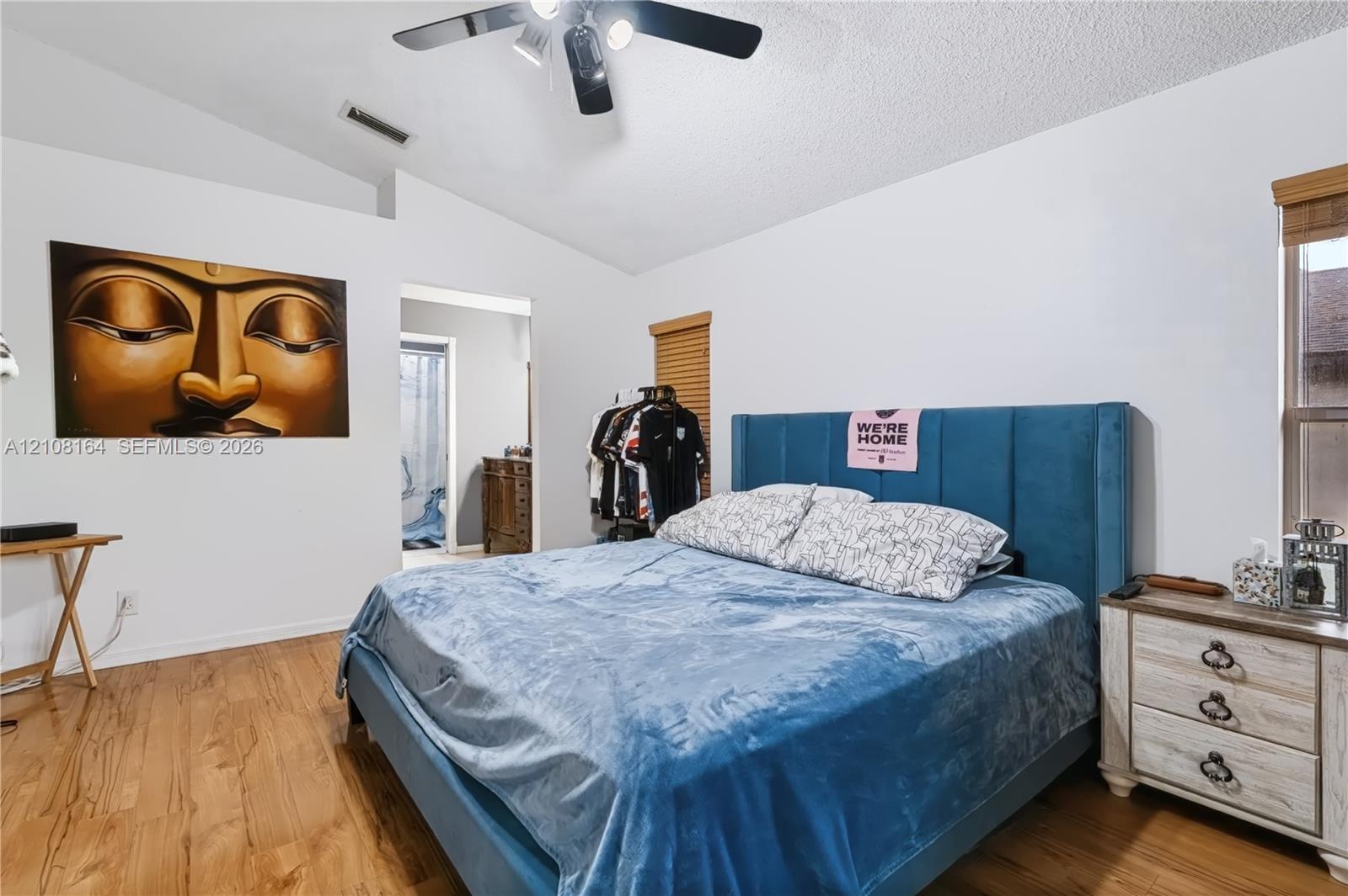 Vaulted ceiling with integrated multi-light ceiling fan, wood-finish flooring, and horizontal window blinds