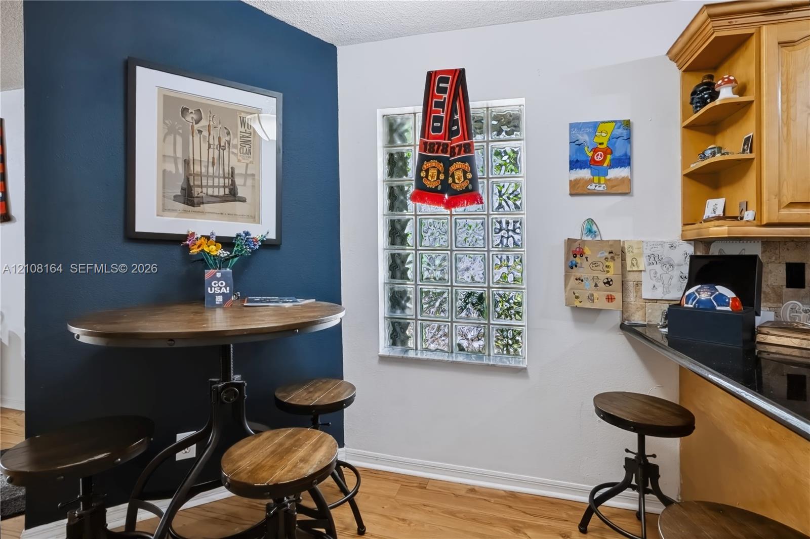 Interior space featuring a dark-toned accent wall, glass block window, wood-finish flooring, and built-in wooden cabinetry with open shelving