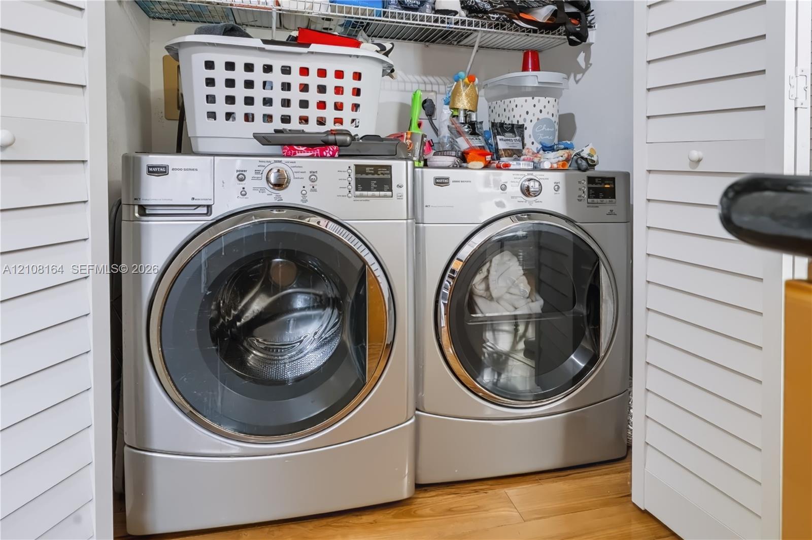 Laundry closet featuring louvered bi-fold doors, wood-finish flooring, and overhead wire shelving