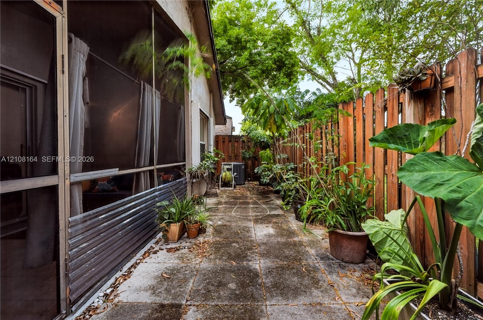 Outdoor patio featuring concrete pavers, a screened-in enclosure, and a wood privacy fence