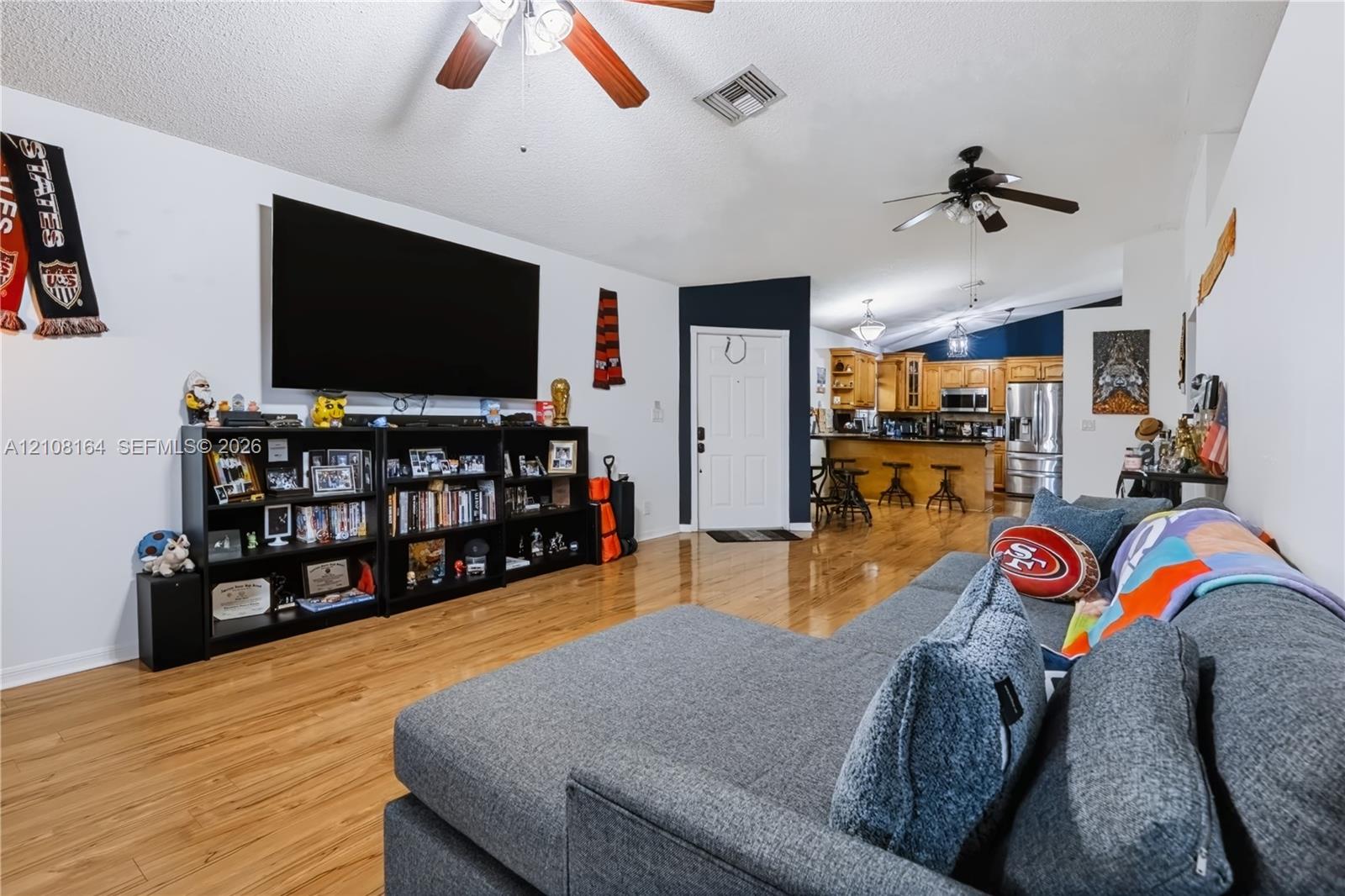 Open-concept interior featuring wood-finish flooring, vaulted ceilings, and dual ceiling fans
