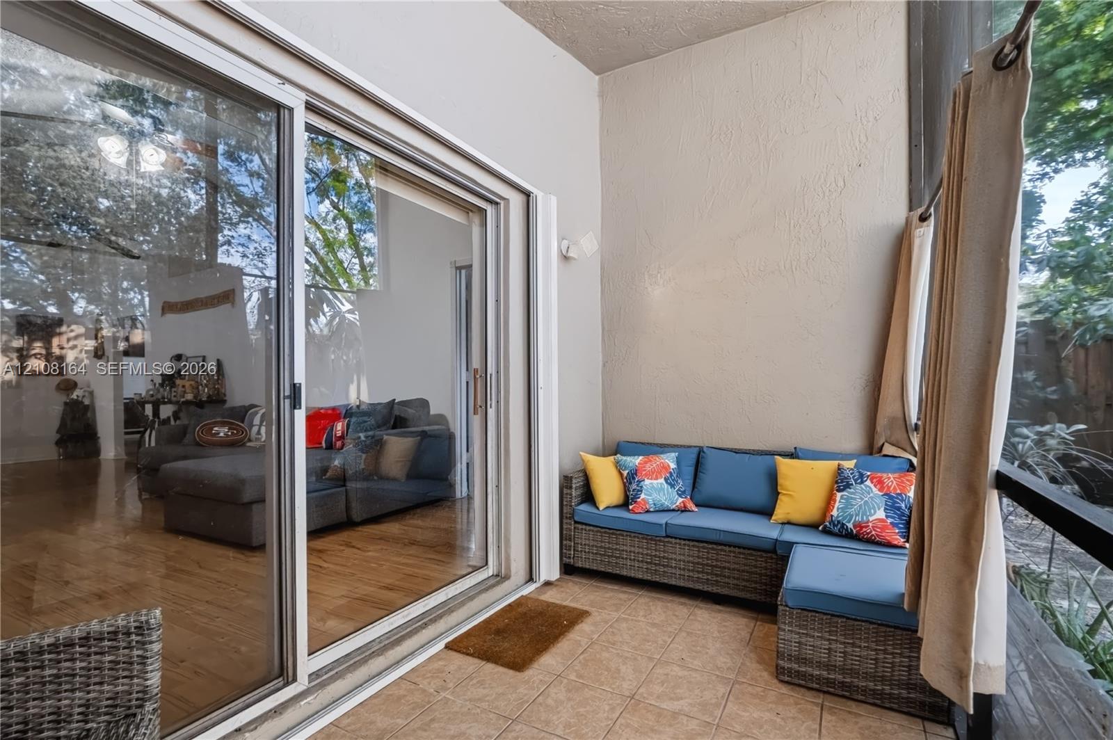 Screened-in patio featuring tile flooring, textured wall finishes, and sliding glass door entry