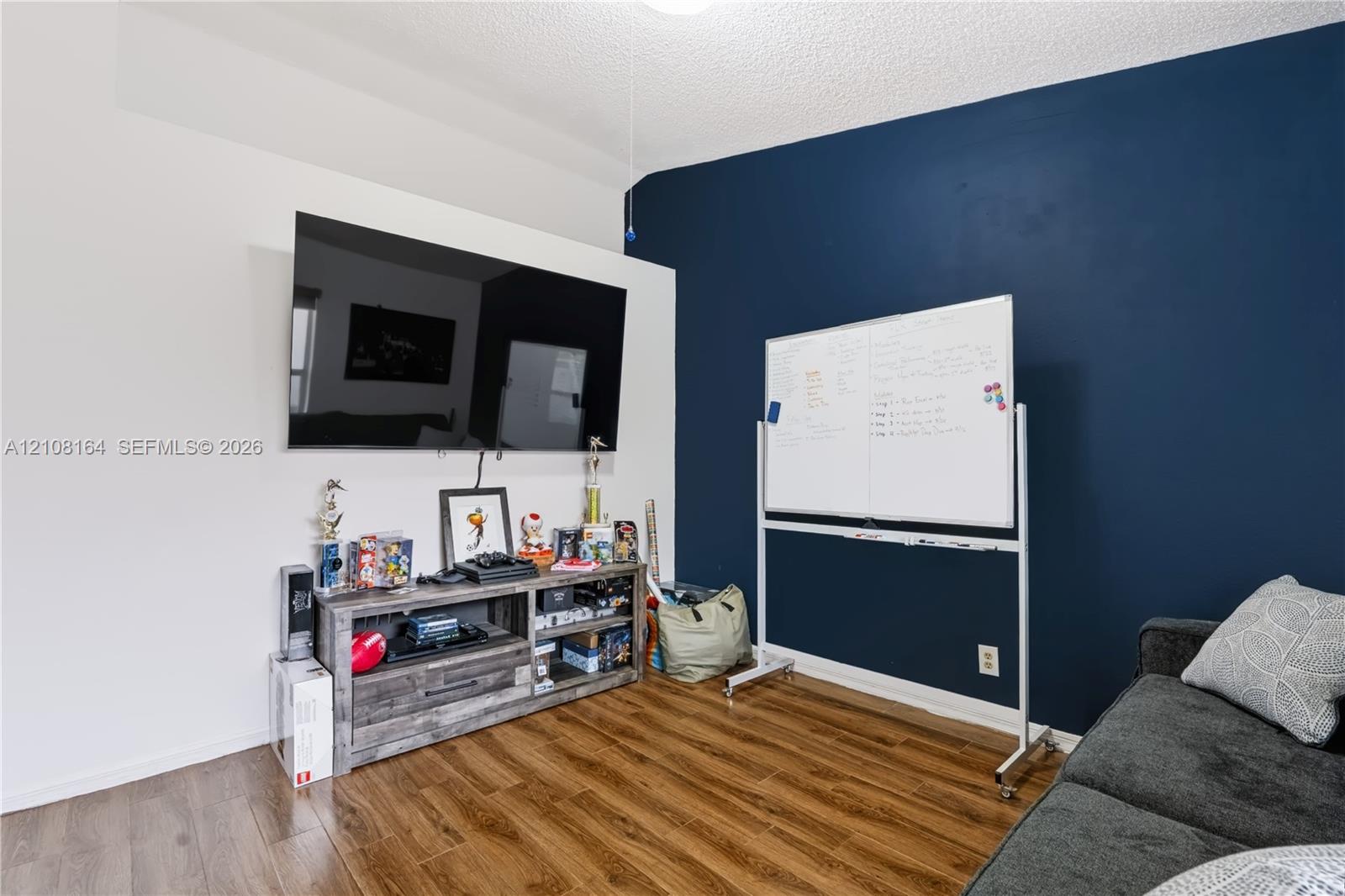 Wood-finish flooring and a high-contrast accent wall featuring a deep navy finish