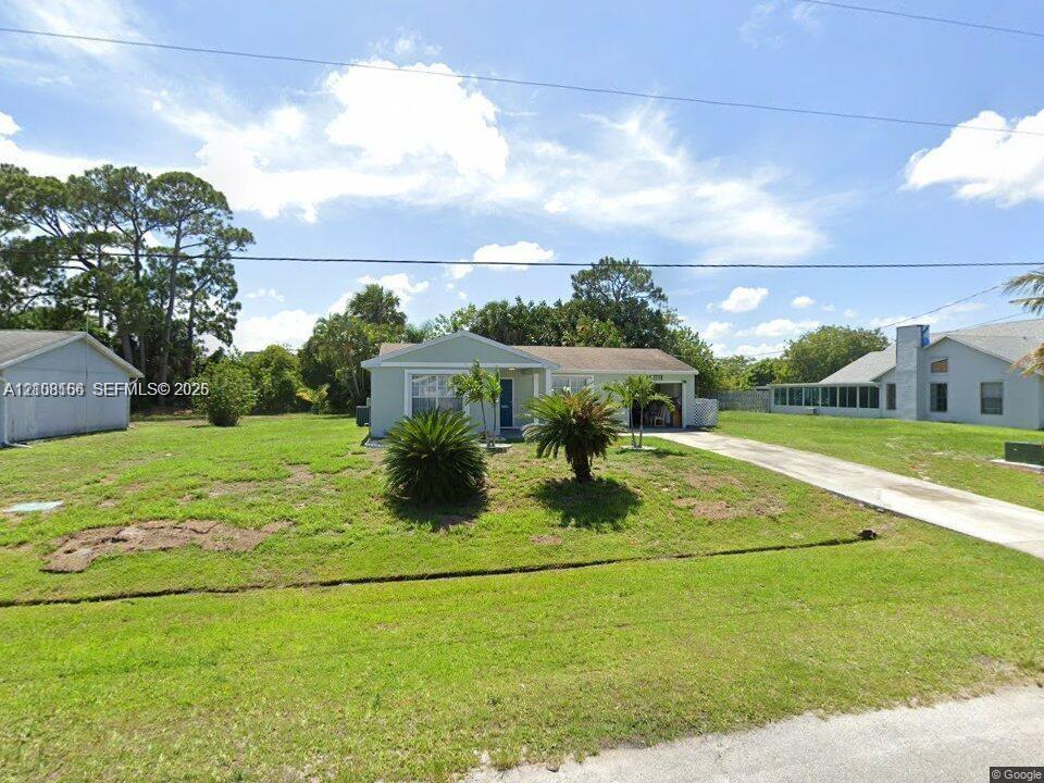Single-story residence featuring a light-toned exterior, concrete driveway, attached garage, and mature landscaping