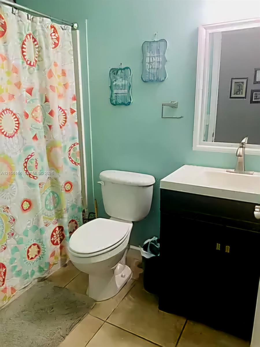 Bathroom featuring a vanity with an integrated rectangular sink, single-handle chrome faucet, wall-mounted mirror, and ceramic tile flooring