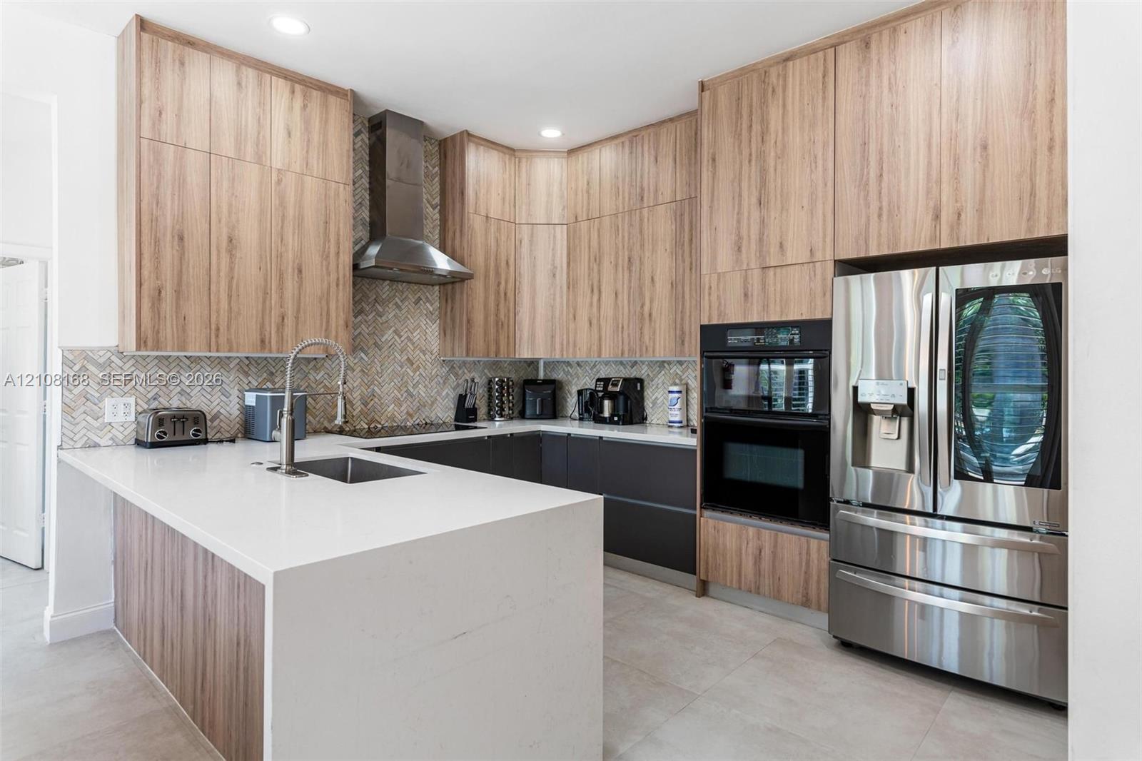 Kitchen featuring wood-finish cabinetry, stone-surface countertops, a herringbone tile backsplash, stainless steel appliances, and a built-in oven