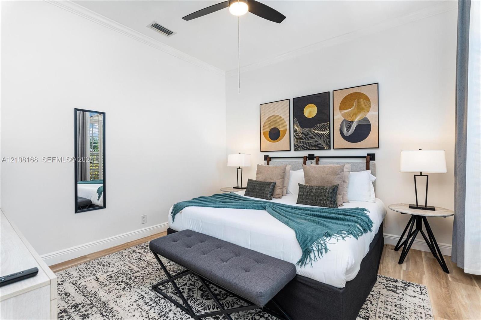 Neutral interior featuring white walls, wood-finish flooring, crown molding, and a ceiling fan with integrated lighting