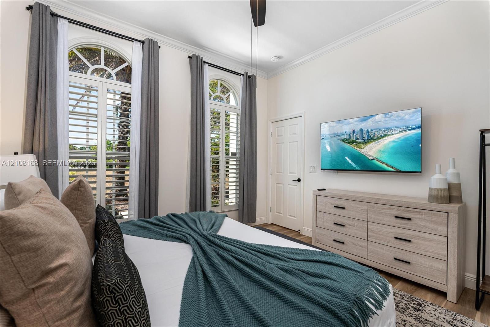 High ceilings with crown molding, arched windows, plantation shutters, and multi-panel interior doors