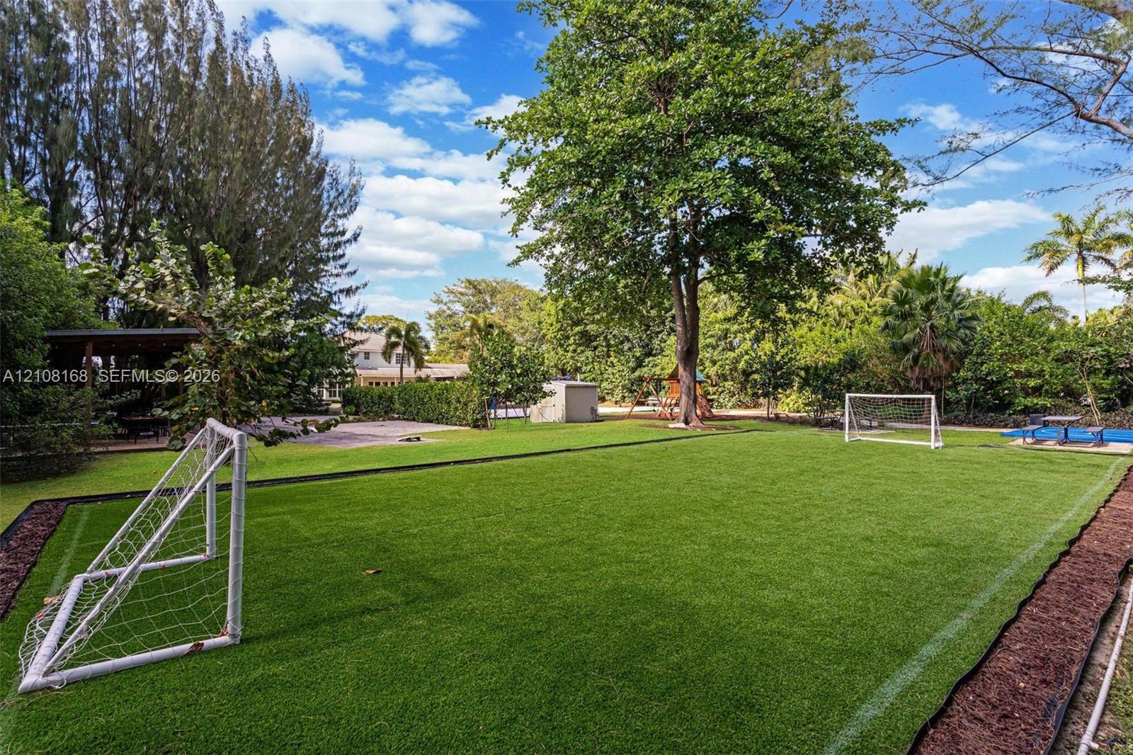 Expansive turf recreation area featuring built-in boundary lining, dual athletic goals, and mature perimeter trees