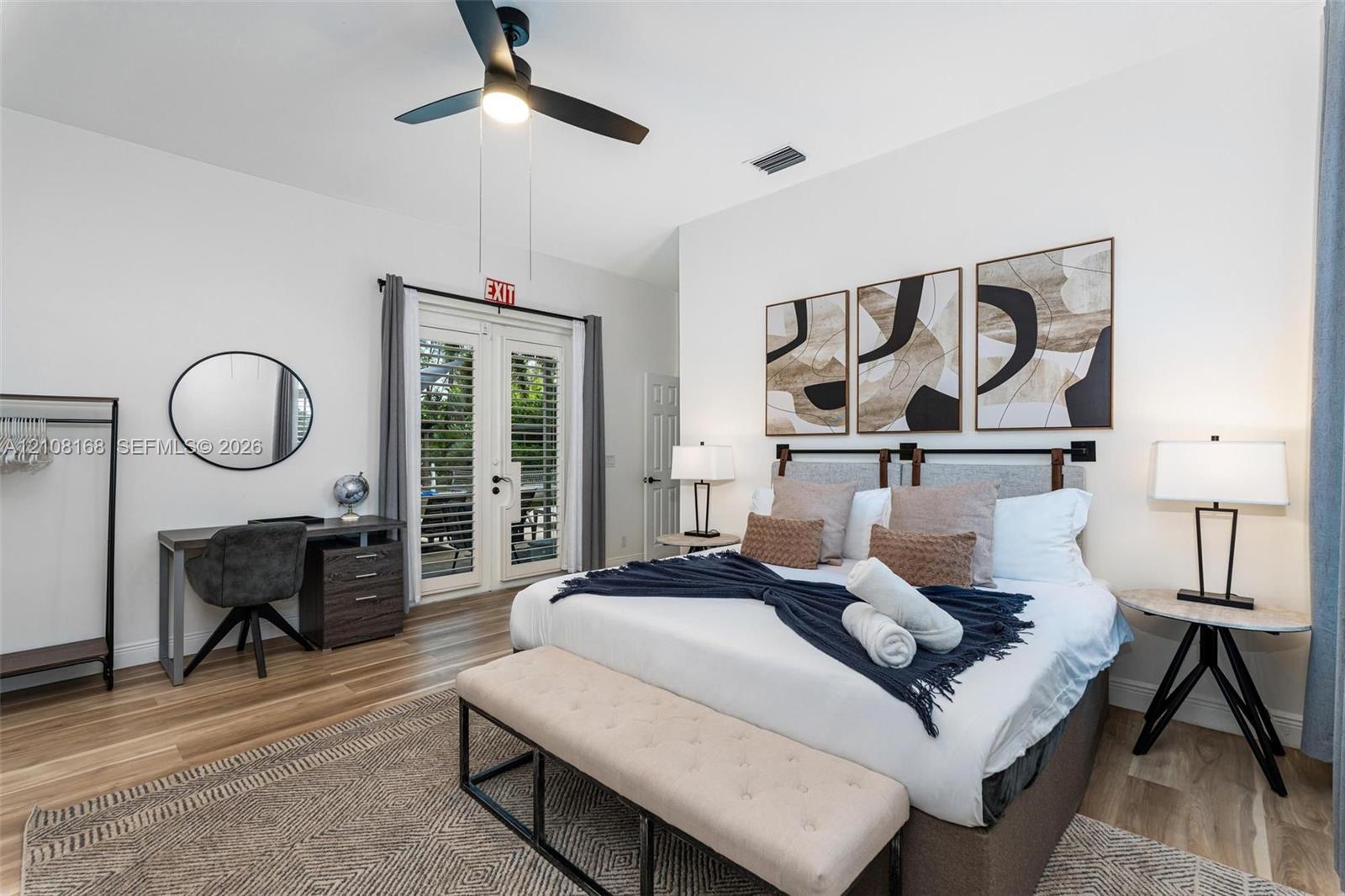 Room featuring wood-finish flooring, vaulted ceilings, a central ceiling fan with integrated lighting, and full-glass French doors with plantation shutters