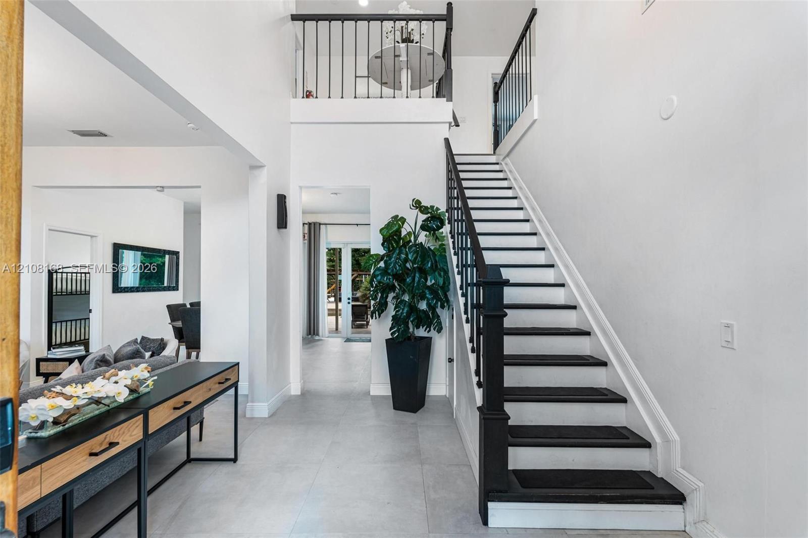 Two-story foyer featuring porcelain tile flooring, a staircase with dark-finished treads and balusters, and a balcony overlook