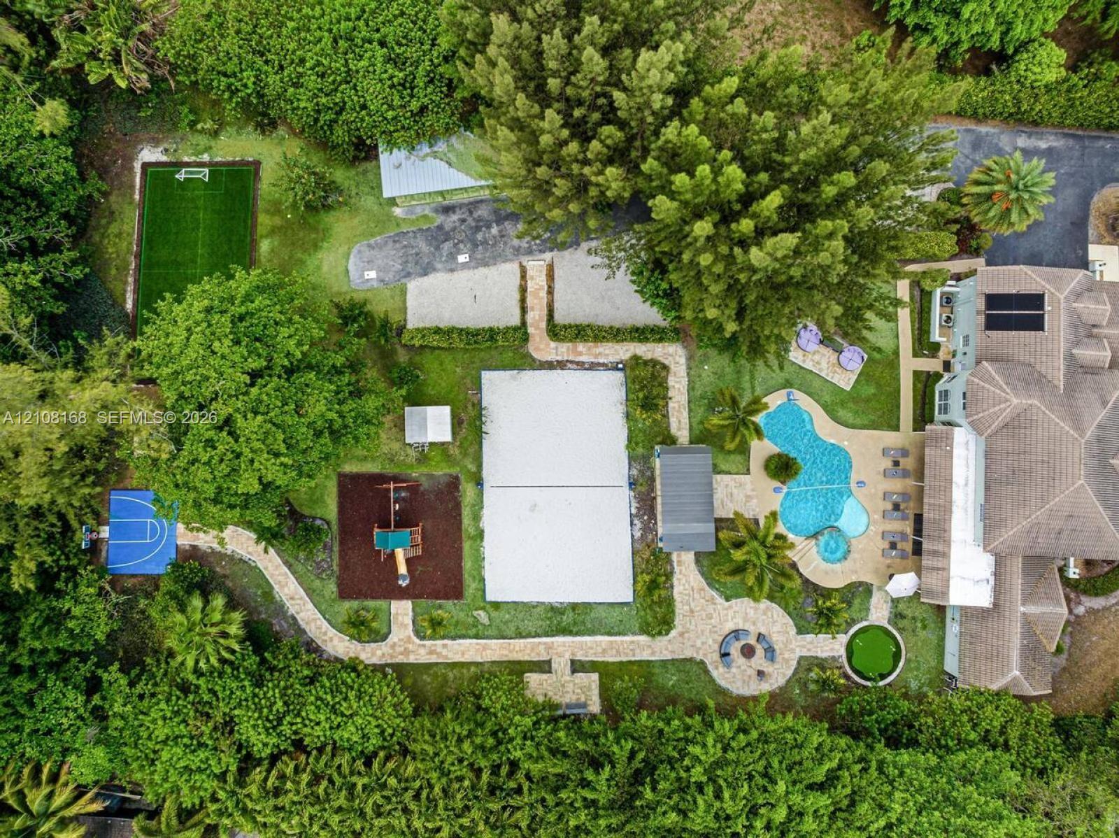 Expansive grounds featuring a swimming pool with integrated spa, multi-sport court, dedicated pickleball court, turf soccer area, and stone-paver walkways