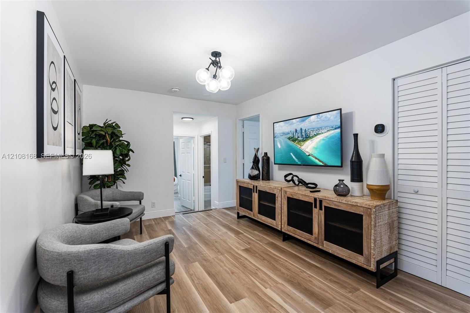 Wood-finish flooring, multi-globe chandelier, and white louvered-style closet doors