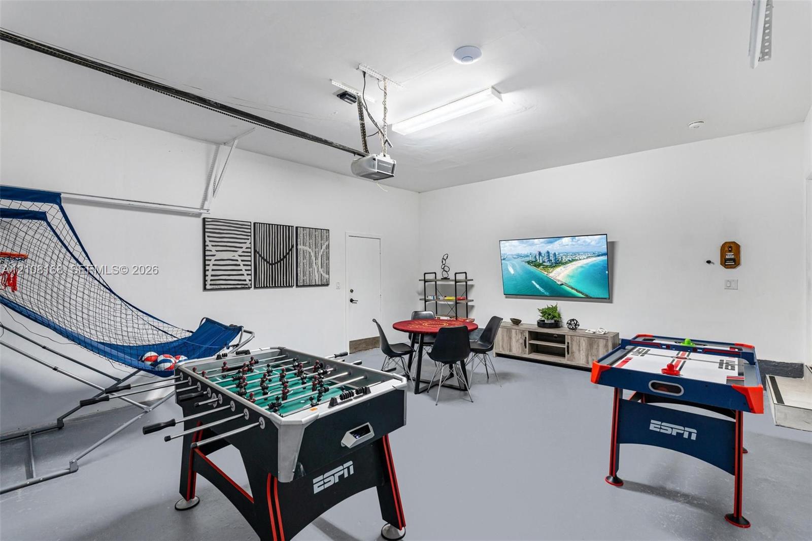 Finished garage space featuring smooth-finish walls, uniform epoxy floor coating, and integrated overhead fluorescent lighting
