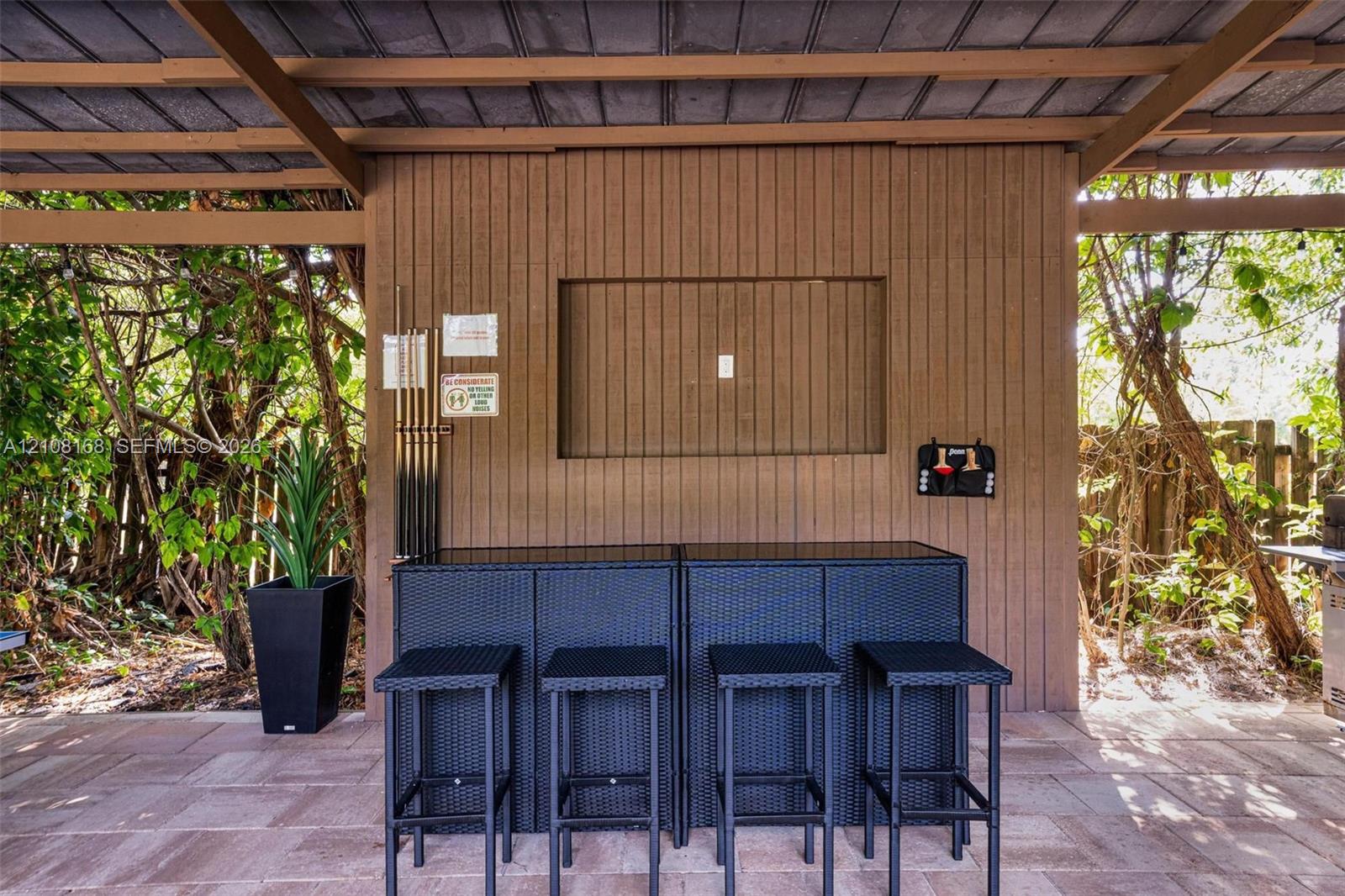 Covered outdoor patio featuring vertical wood-plank siding, stone-paver flooring, and a recessed wall niche