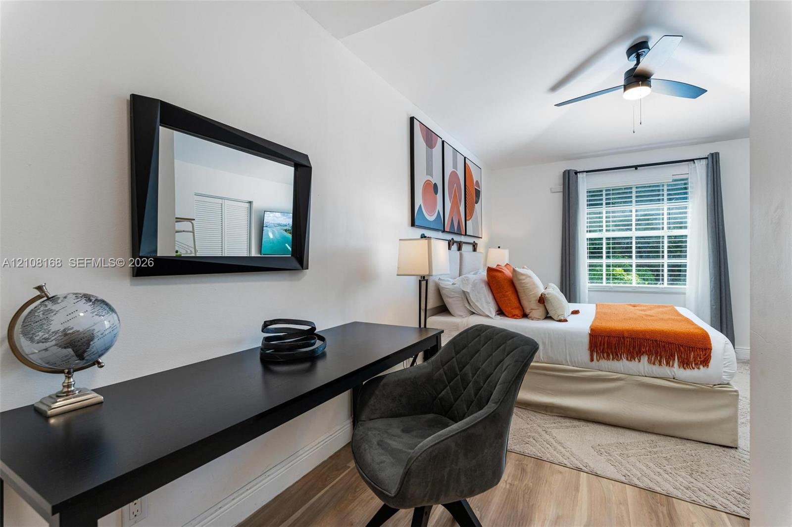 Wood-finish flooring, ceiling fan with integrated lighting, and window with muntins