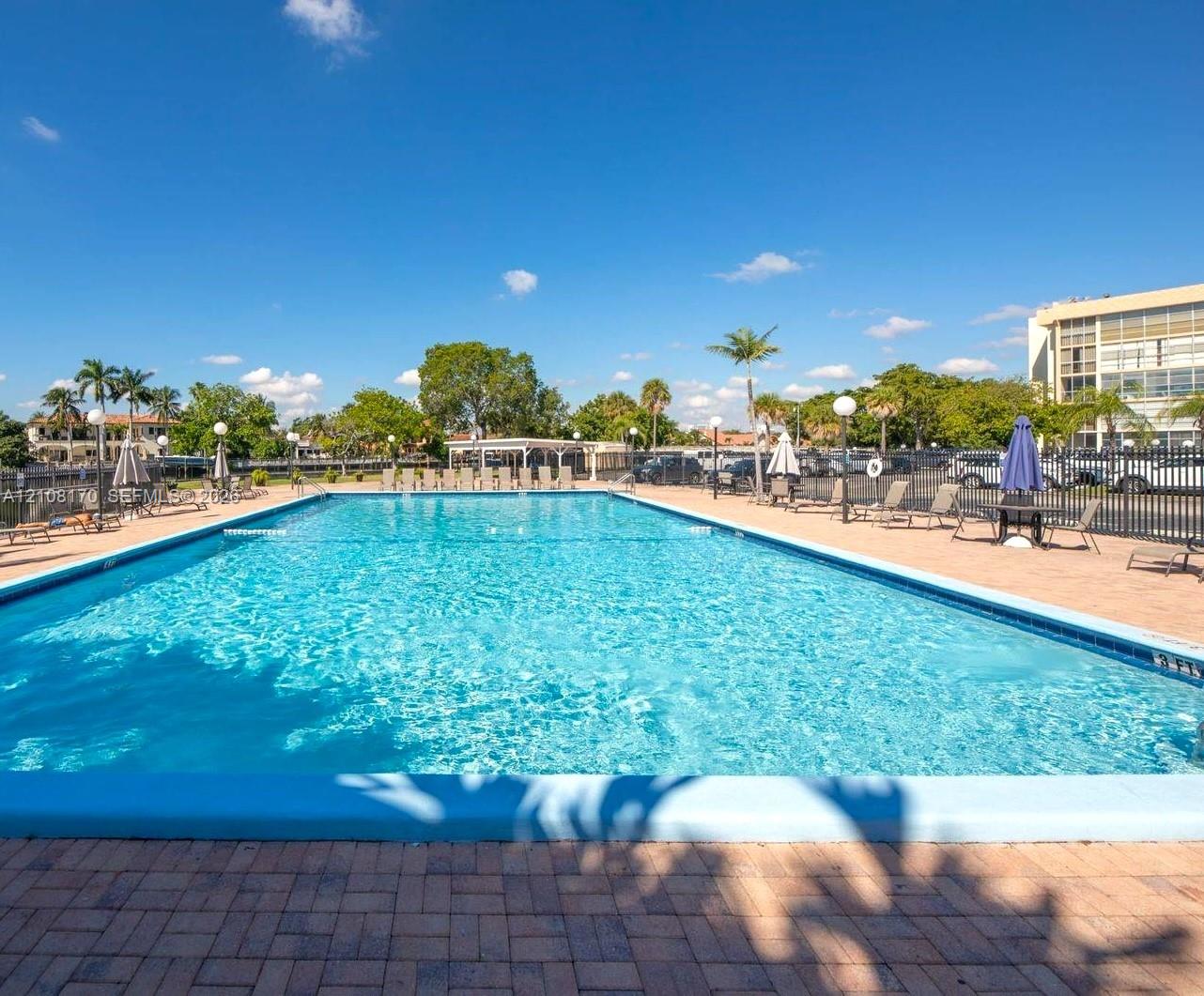 Rectangular in-ground swimming pool with a stone paver deck and metal perimeter fencing