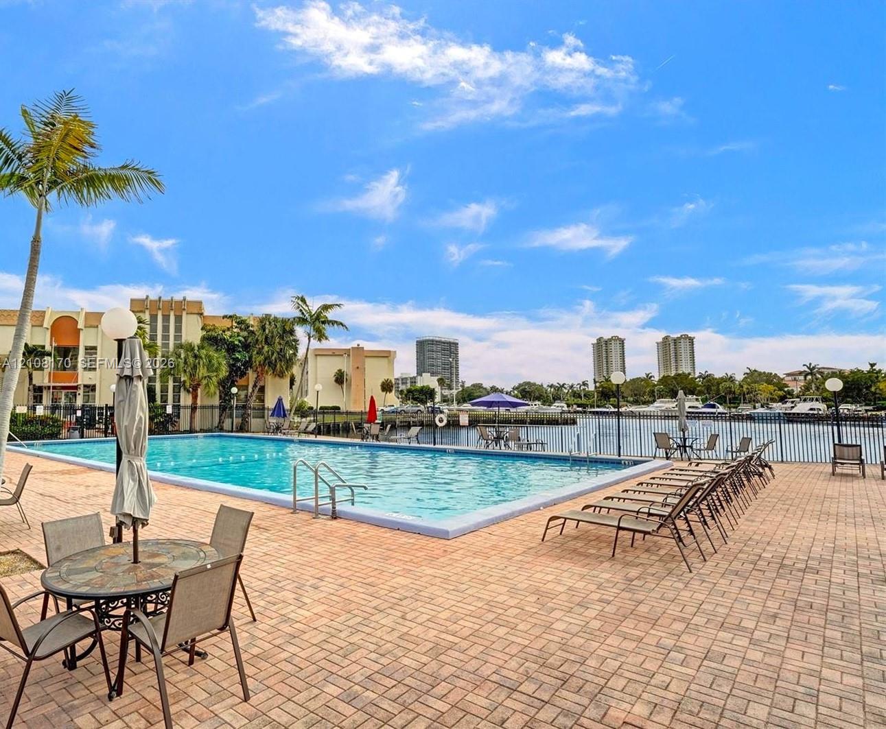 In-ground swimming pool with metal fencing, brick paver decking, and waterfront access
