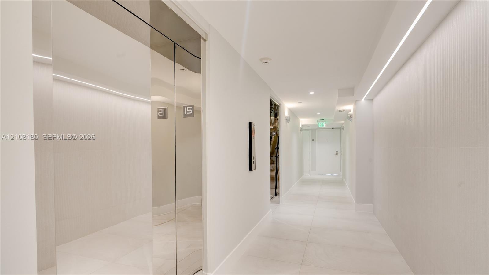 Polished chrome elevator doors, textured wall cladding, large-format tile flooring, and integrated linear LED ceiling lighting Polished chrome elevator doors, textured wall cladding, large-format tile flooring, and integrated linear LED ceiling lighting