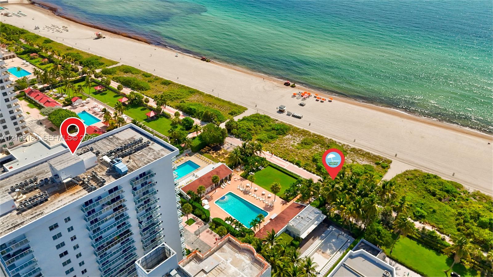 Aerial perspective of a high-rise building situated on a direct beachfront property, featuring an outdoor swimming pool, paved sundeck, and landscaped lawn areas Aerial perspective of a high-rise building situated on a direct beachfront property, featuring an outdoor swimming pool, paved sundeck, and landscaped lawn areas
